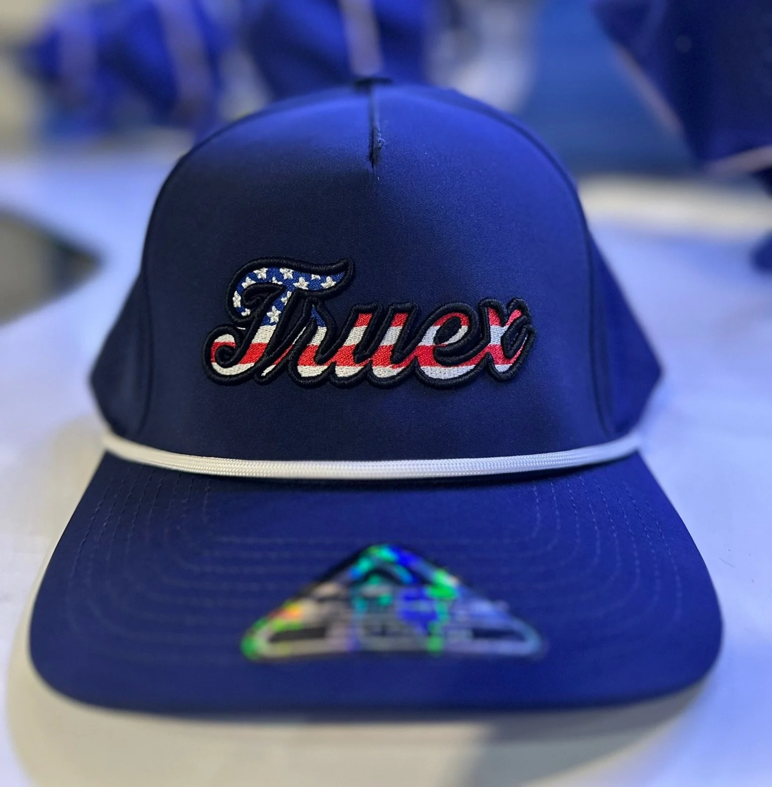 Blue baseball cap with embroidered 'Trump' in American flag colors and stars.