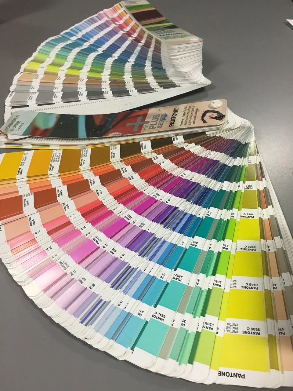 Color swatch fan deck displaying a variety of paint color samples arranged in a fan shape on a gray surface.
