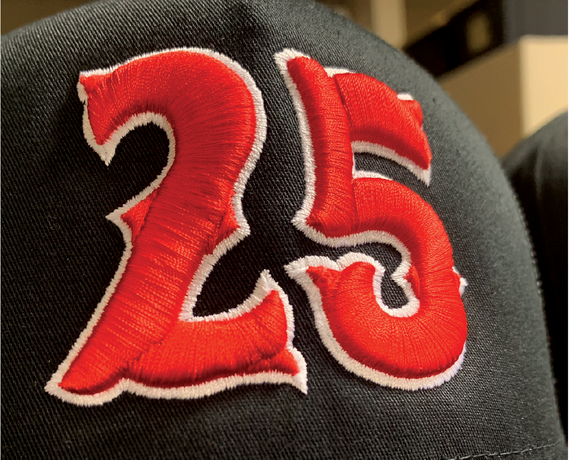 Close-up of a black fabric with red embroidered number 23 outlined in white.