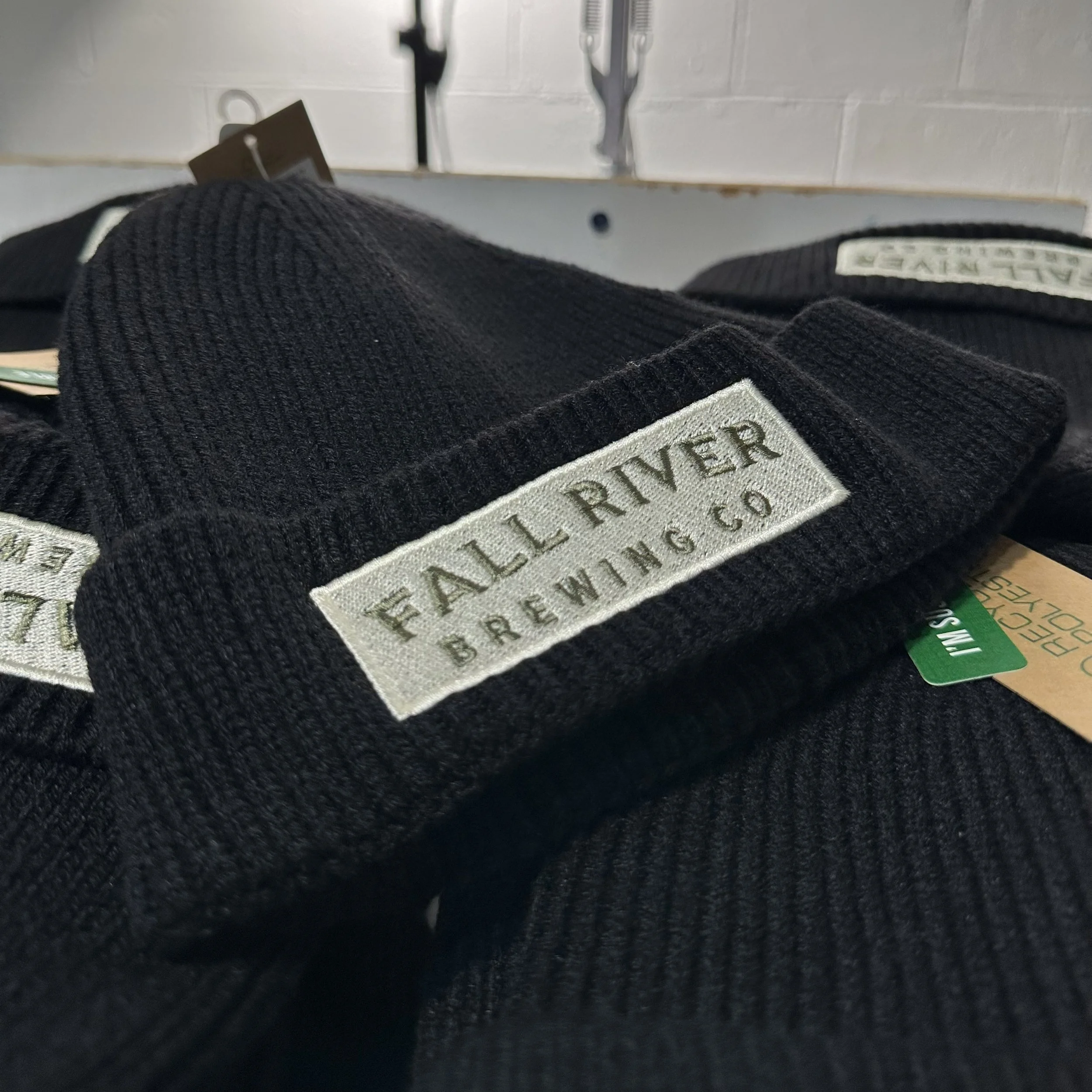 Close-up of a black fabric label with white embroidered text on a pair of black shoes.