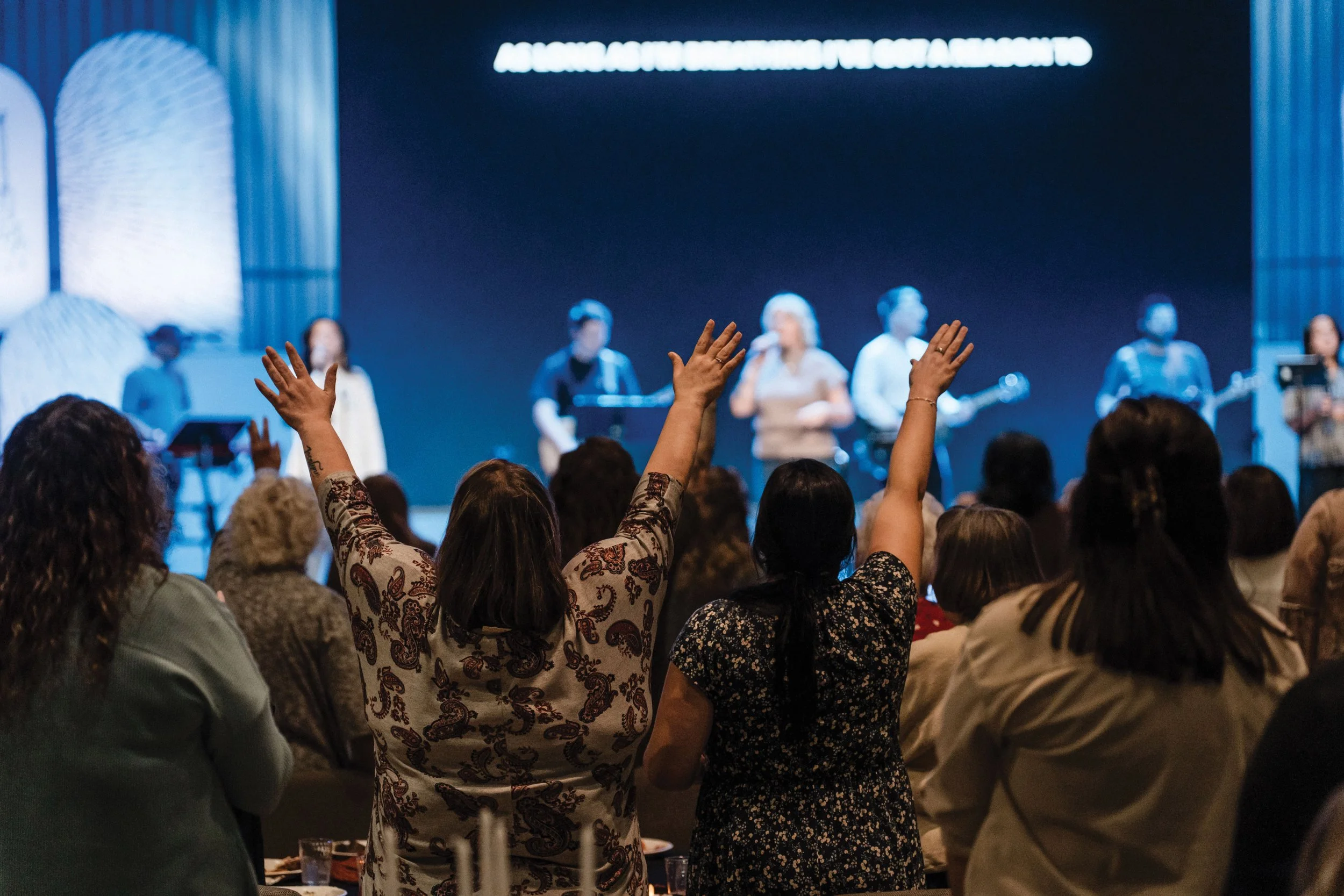 A group of parishioners worship with their arms outstretched towards Union Chapel's main stage.