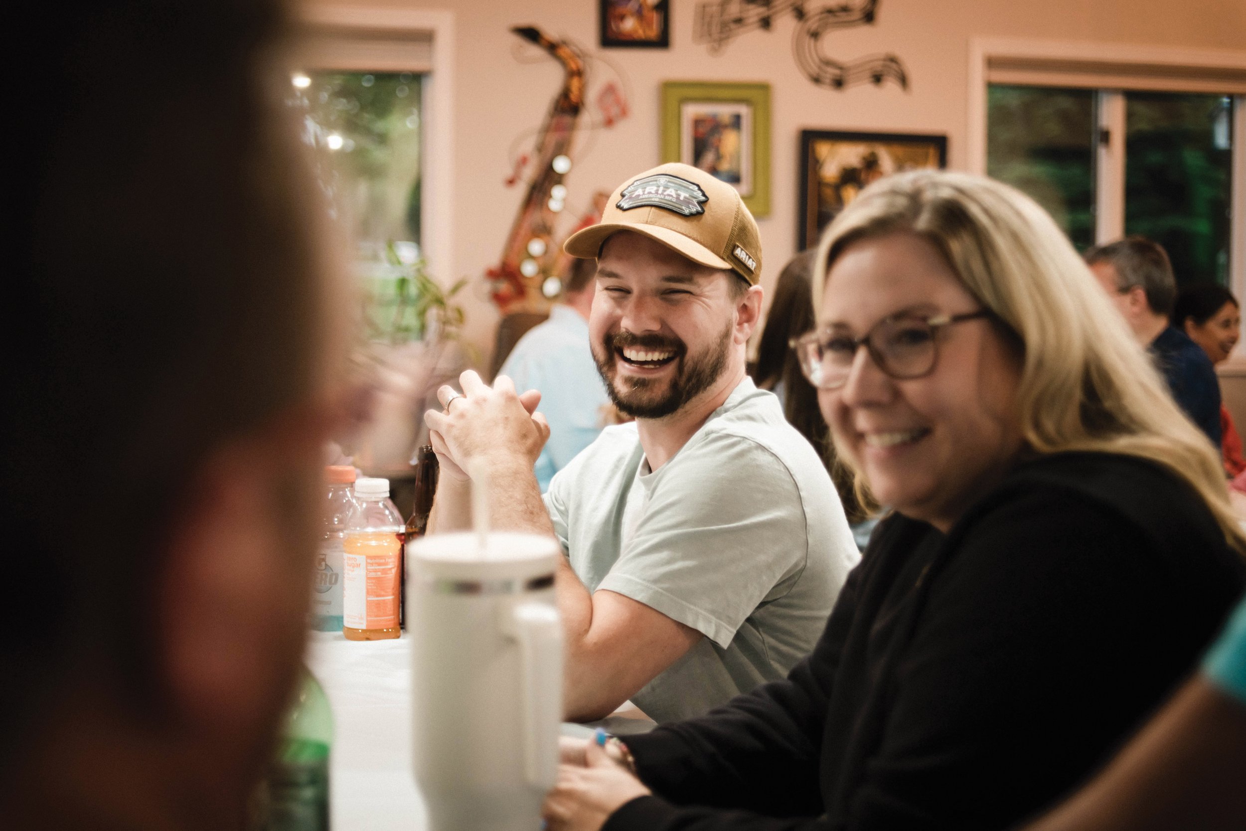 A group of two adults in a small group look off in the distance, smiling and laughing.