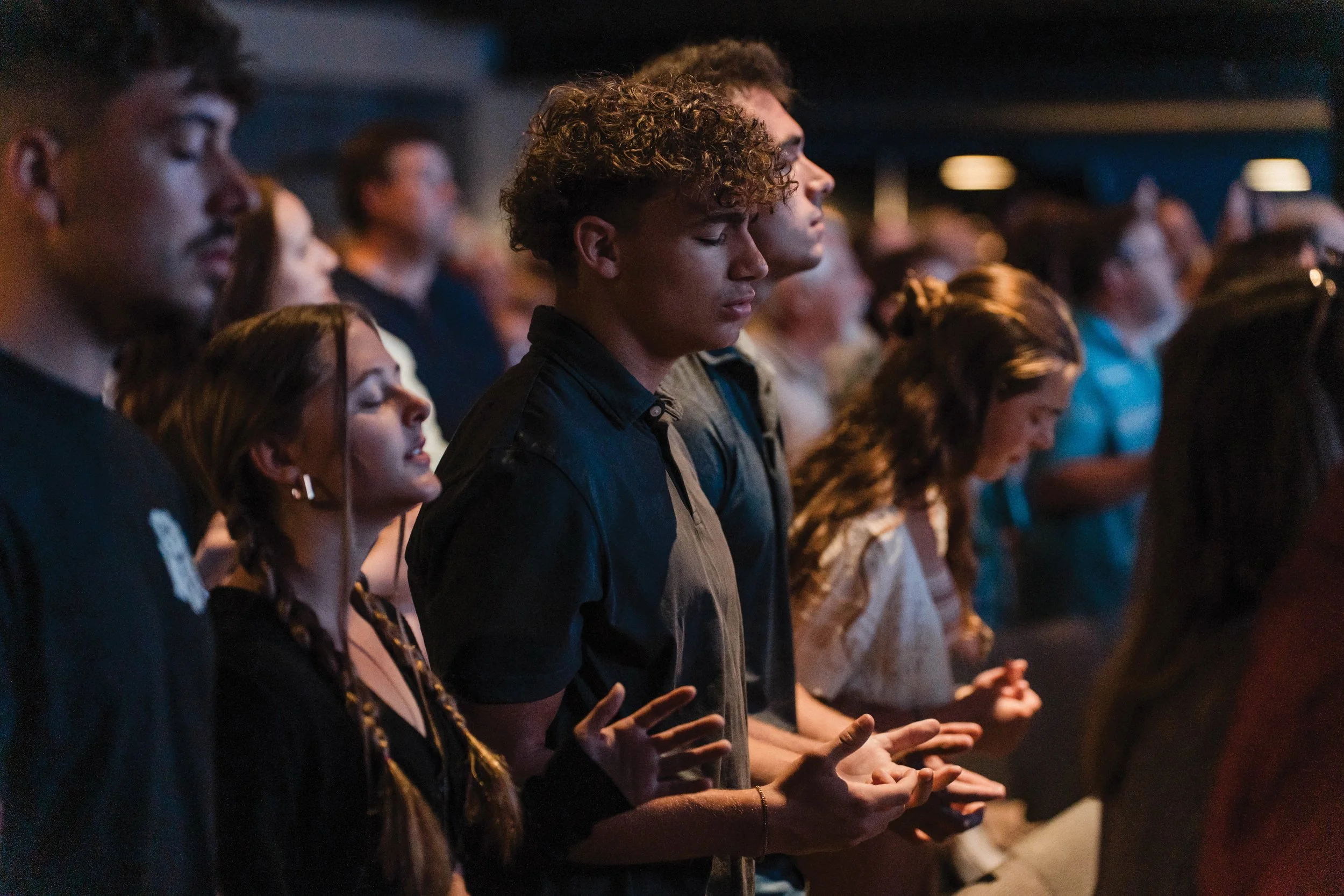 A group of young parishioners assume a posture of prayer and reflection.