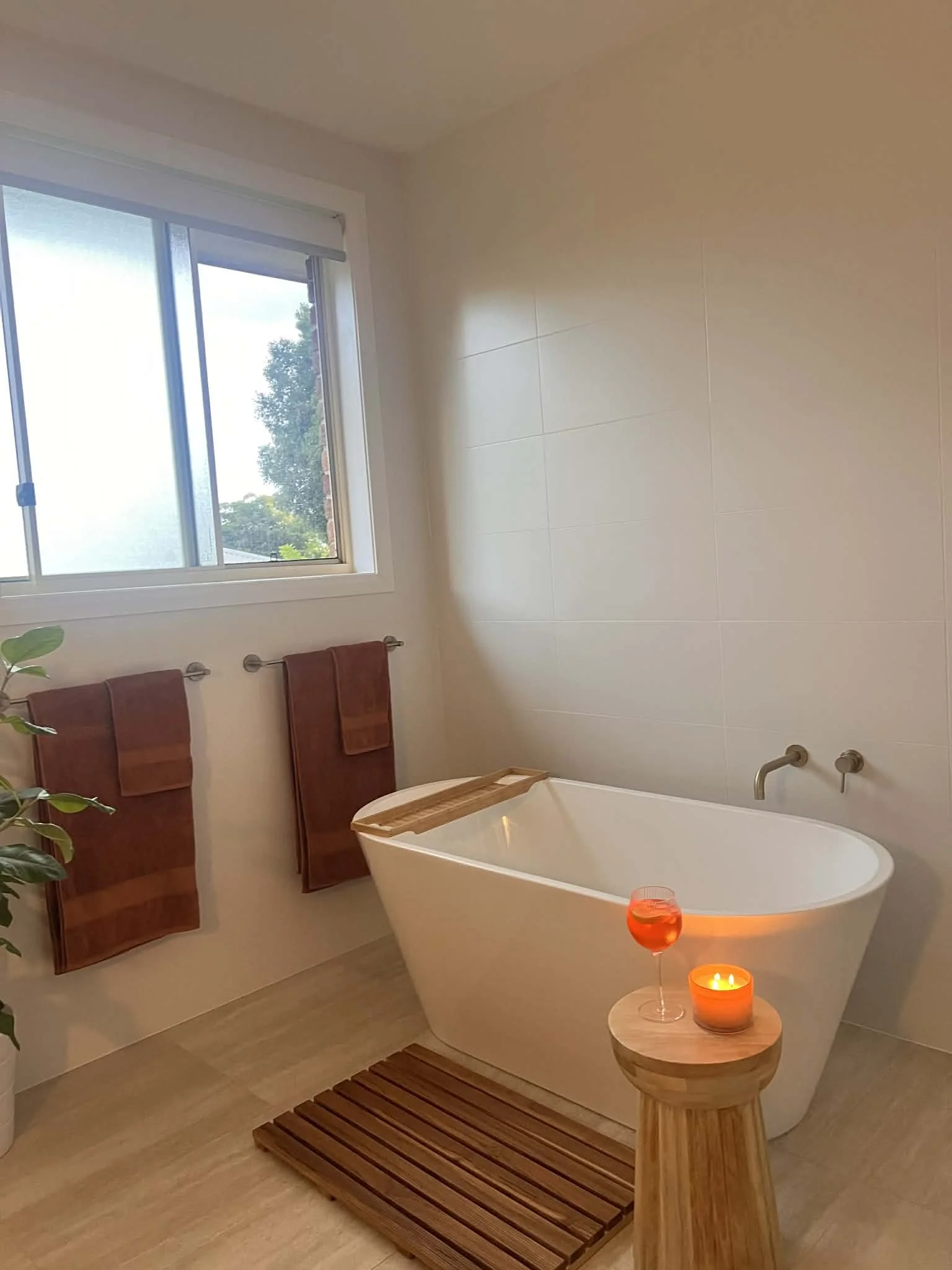 Sandstone floor tiles, large bathtub and brush gold hardware for the bathroom redesigned by Bortolazzo Interior Design