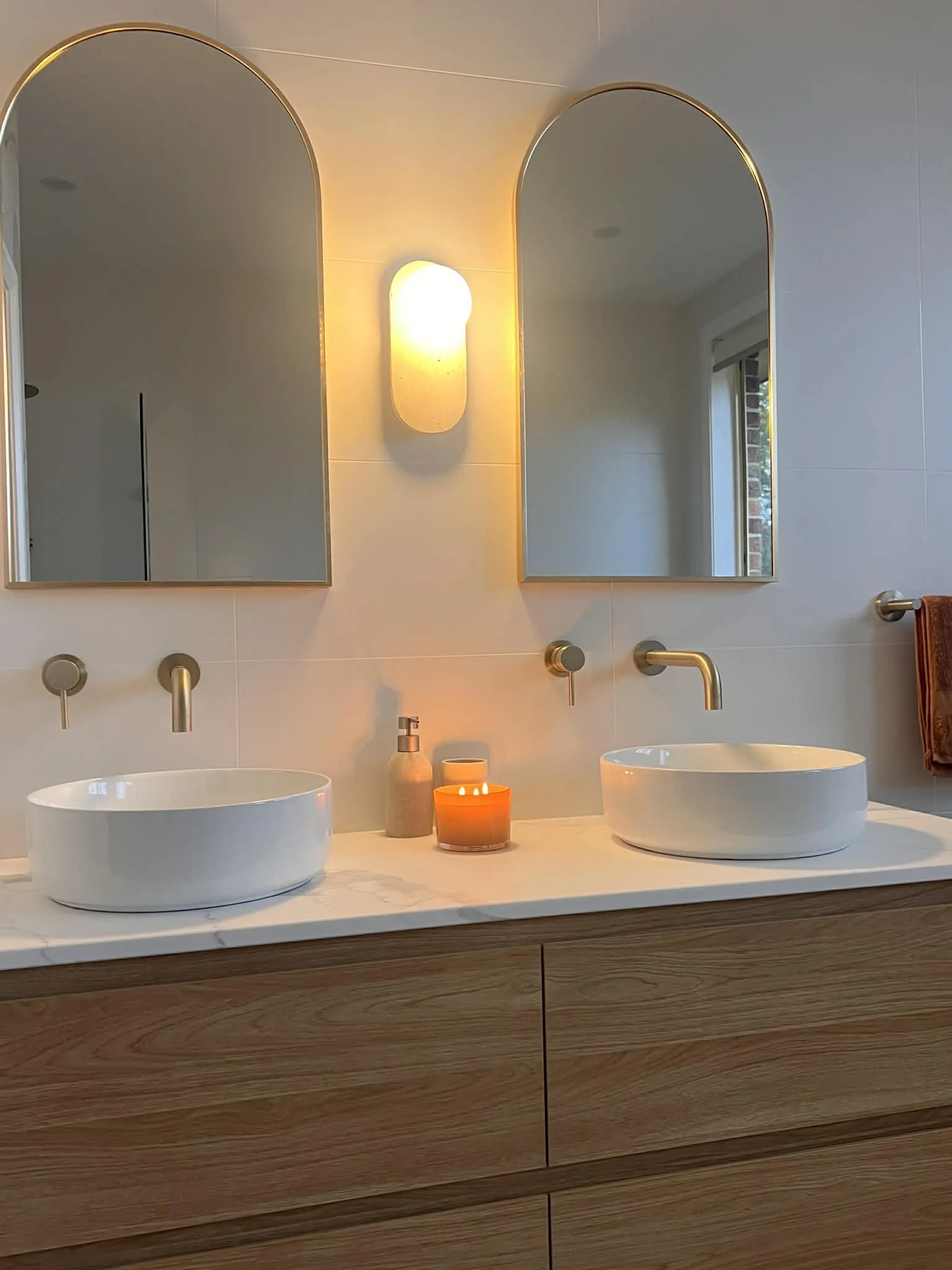 Modern double sink basin, mirrors, sconce, tap ware, tiled finish, timber draws and styling for the bathroom redesigned by Bortolazzo Interior Design