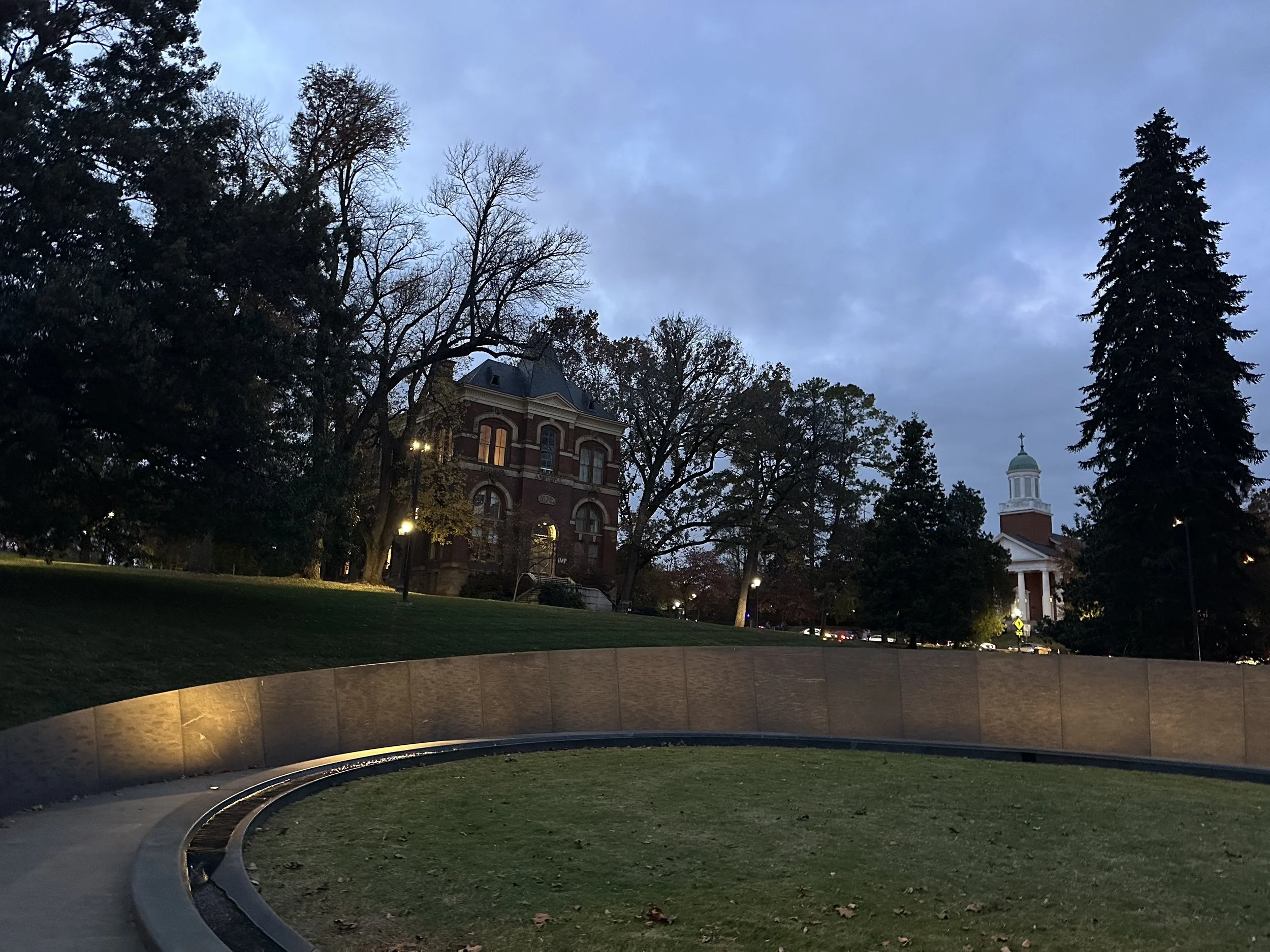 UVA park scene at dusk with old buildings, trees, and streetlights.