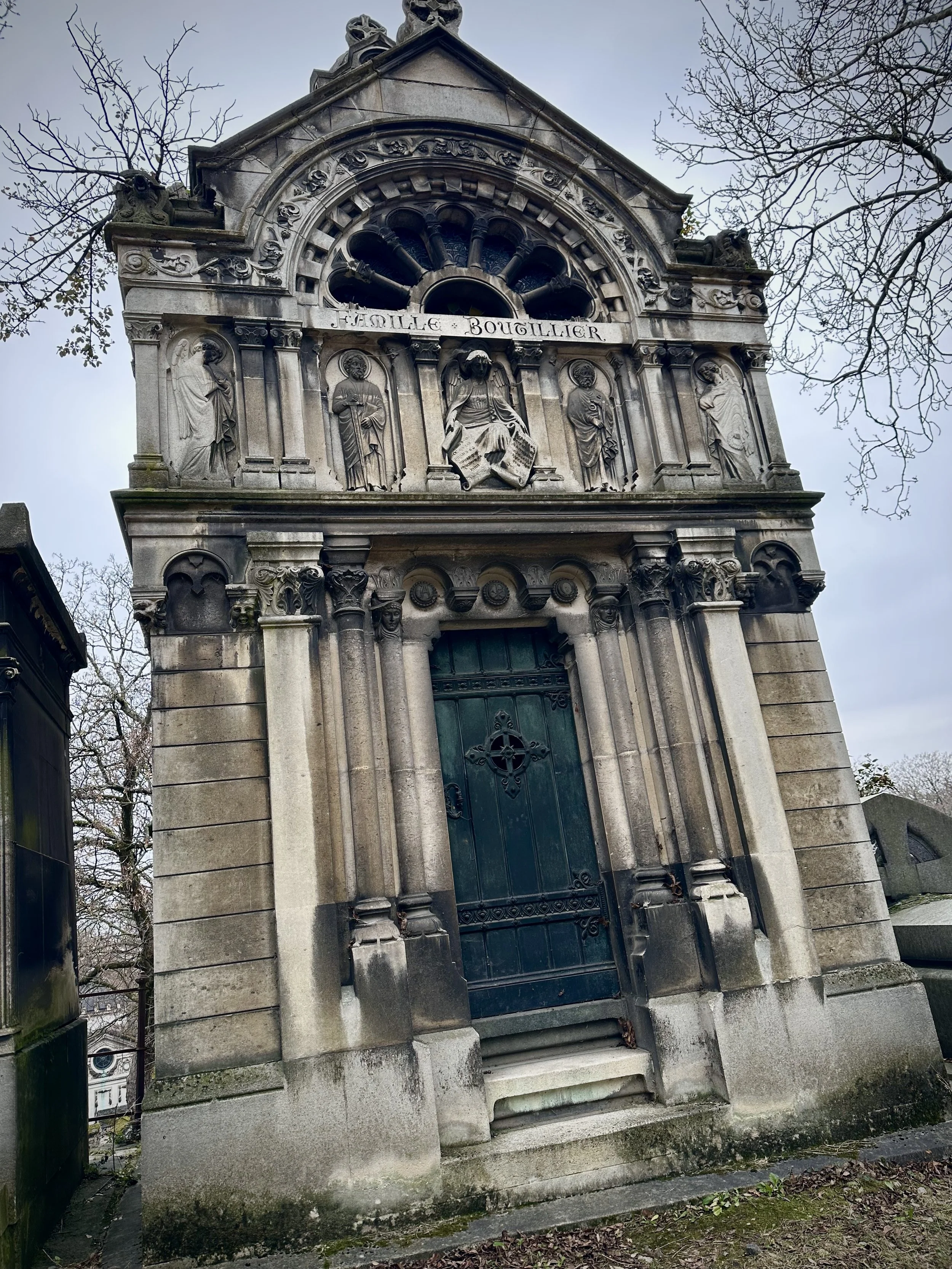 A historic church or mausoleum with gothic architecture, featuring ornate stone carvings, columns, and statues, with the inscription 'Famille Boulillier' above the statues.