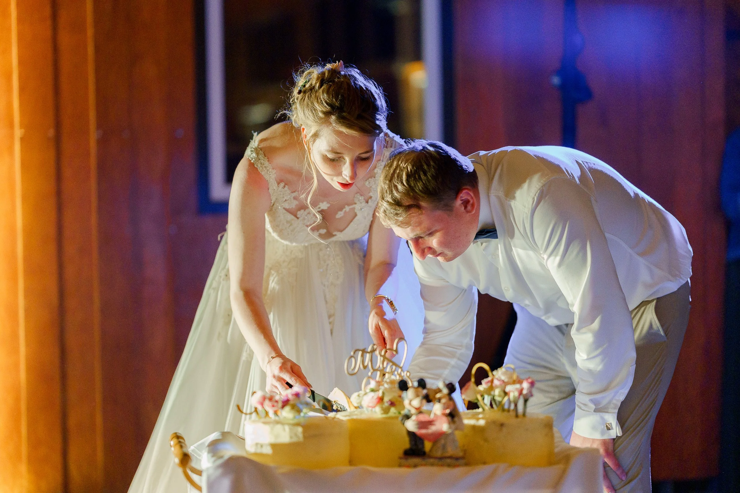 Braut und Bräutigam schneiden an ihrem Hochzeitstag eine Torte gemeinsam.