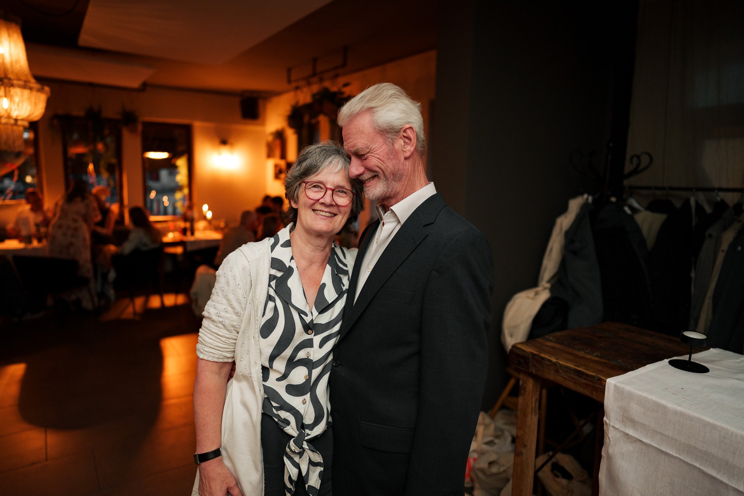 Älteres Paar beim Tanzen in einem festlichen Restaurant, lachend und sich anlächelnd.