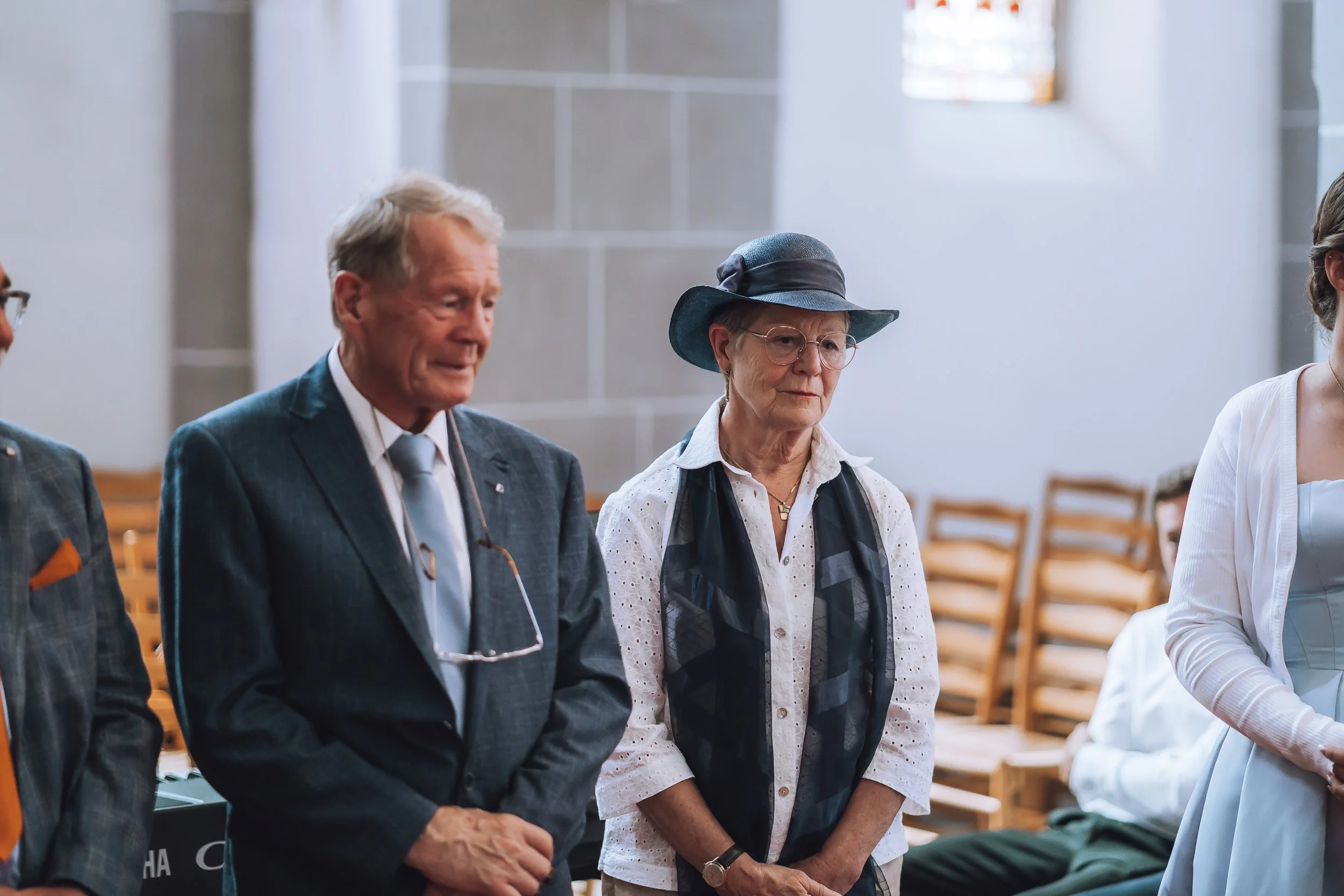 Menschen beim stillen Gebet in einer Kirche, ältere Frauen und Männer stehen mit geschlossenen Augen und respektvoller Haltung.