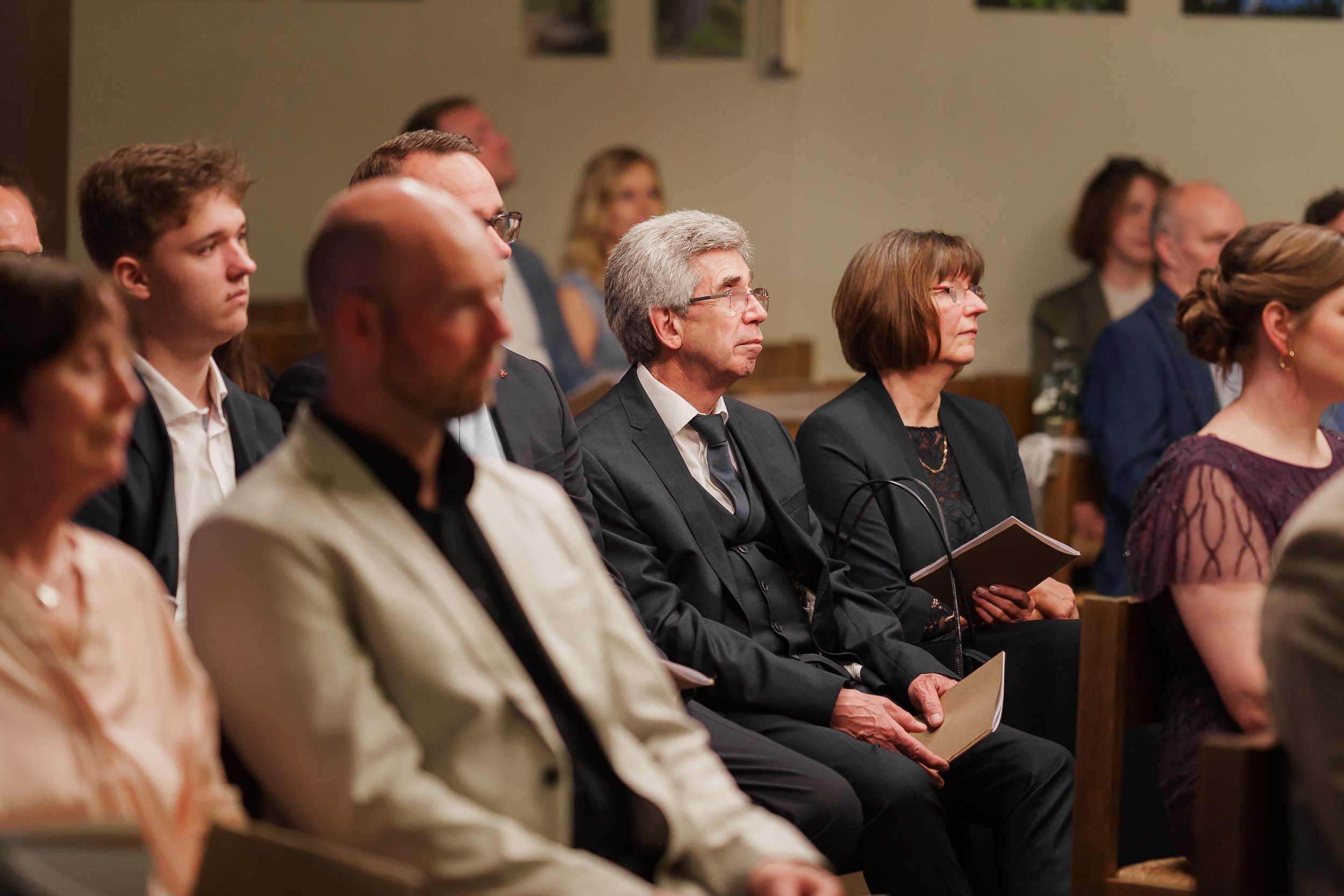 Menschen sitzen in einem Saal bei einer Veranstaltung und hören aufmerksam zu.