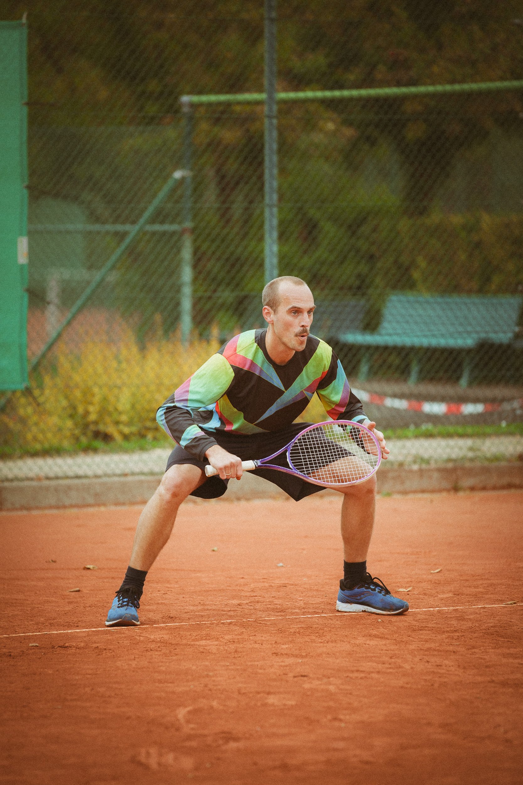 Mann auf Tennisplatz in Sportswear mit Tennisschläger in Bereitschaft in Haltung