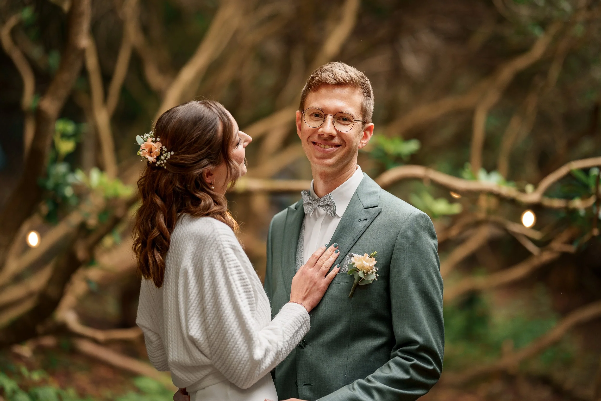Ein glückliches Paar bei einer Hochzeit in einem grünen, bewachsenen Wald.