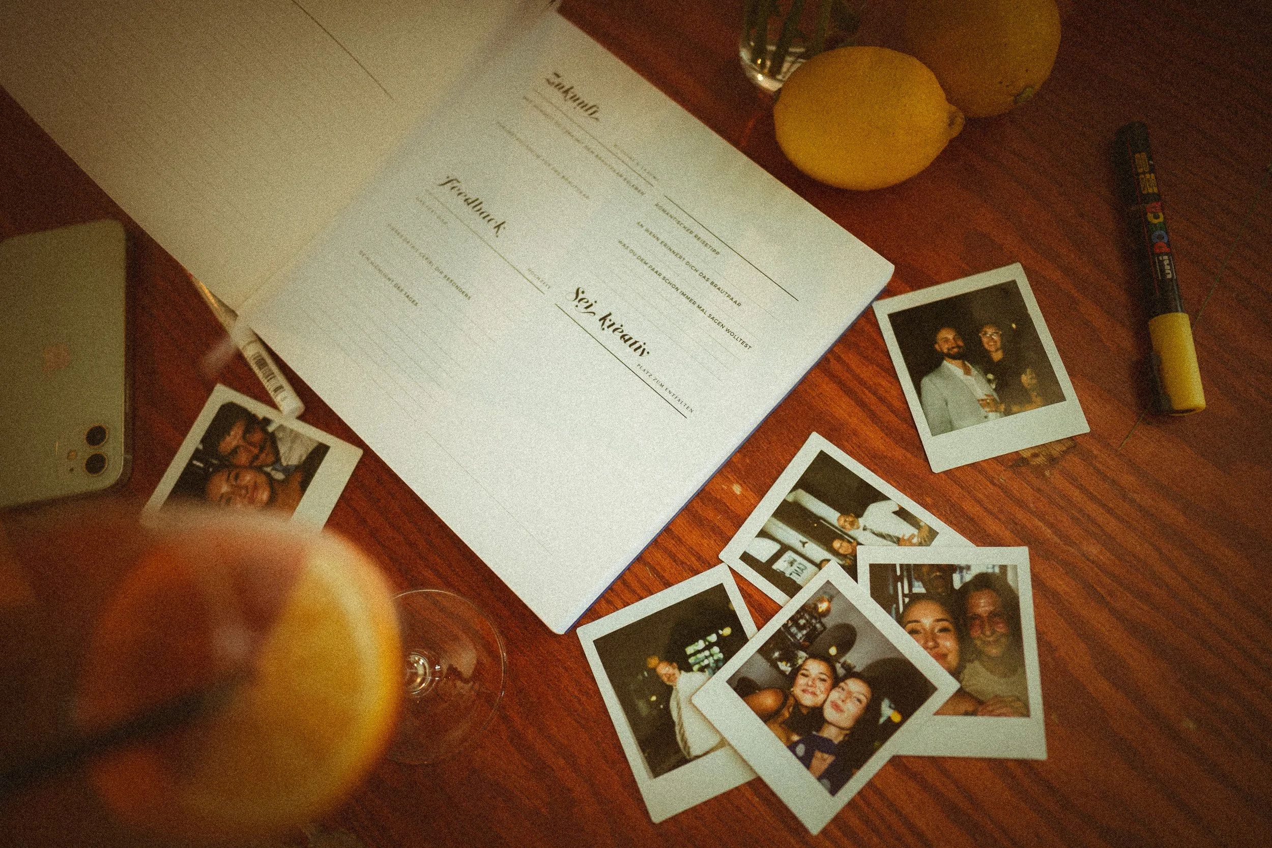 Ein Tisch mit Zitronen, Fotos, einem Klemmbrett, einem Stift, einem Smartphone und einem Glas Wasser. Auf dem Klemmbrett liegt eine leere Formularvorlage, die zum Ausfüllen bereit ist.