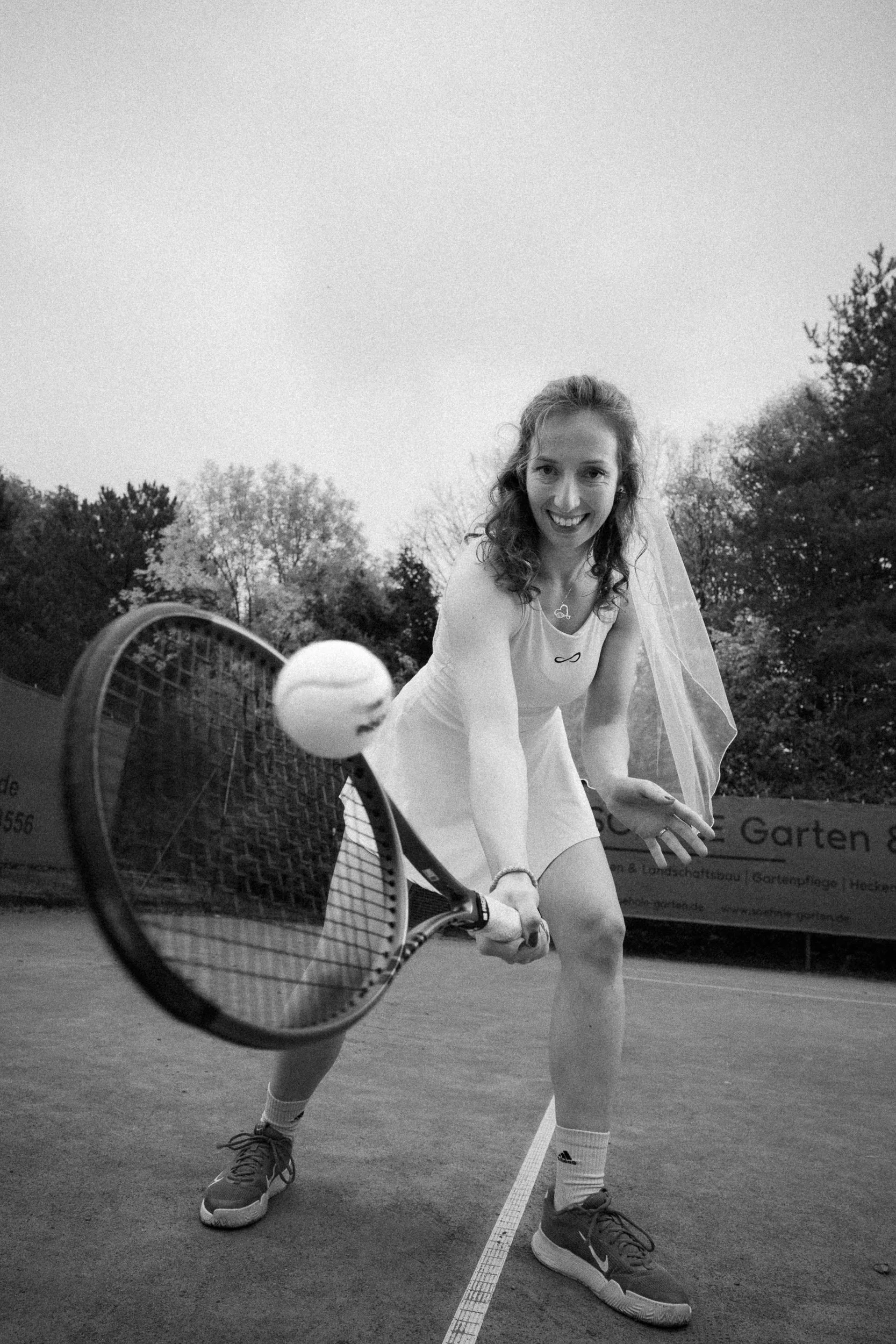 Junge Frauen im Hochzeitskleid beim Tennis auf dem Tennisplatz
