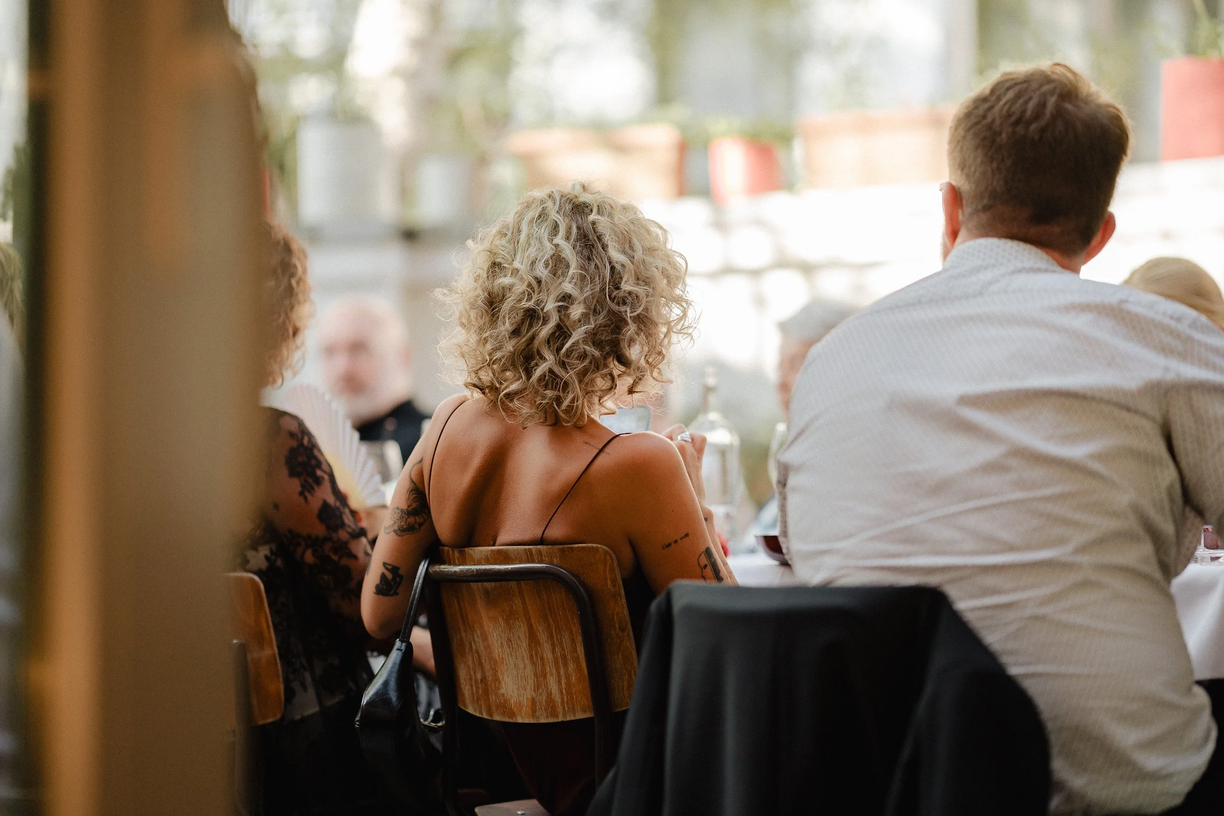 Menschen sitzen an einem Tisch bei einem Essen in einem hell erleuchteten Raum mit Fenster im Hintergrund.