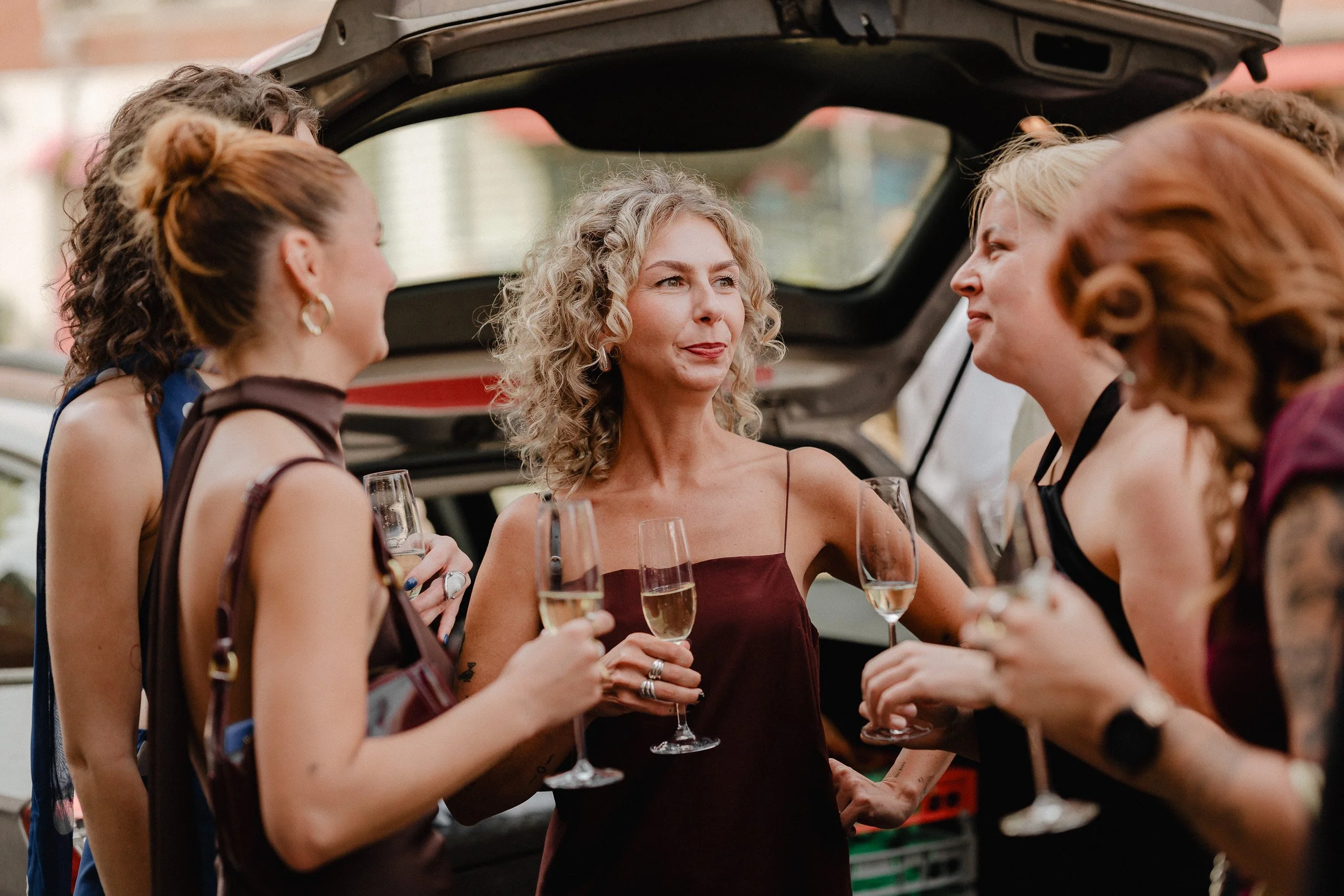Gruppe eleganter Frauen beim Empfang mit Champagner bei einer Party im Freien.