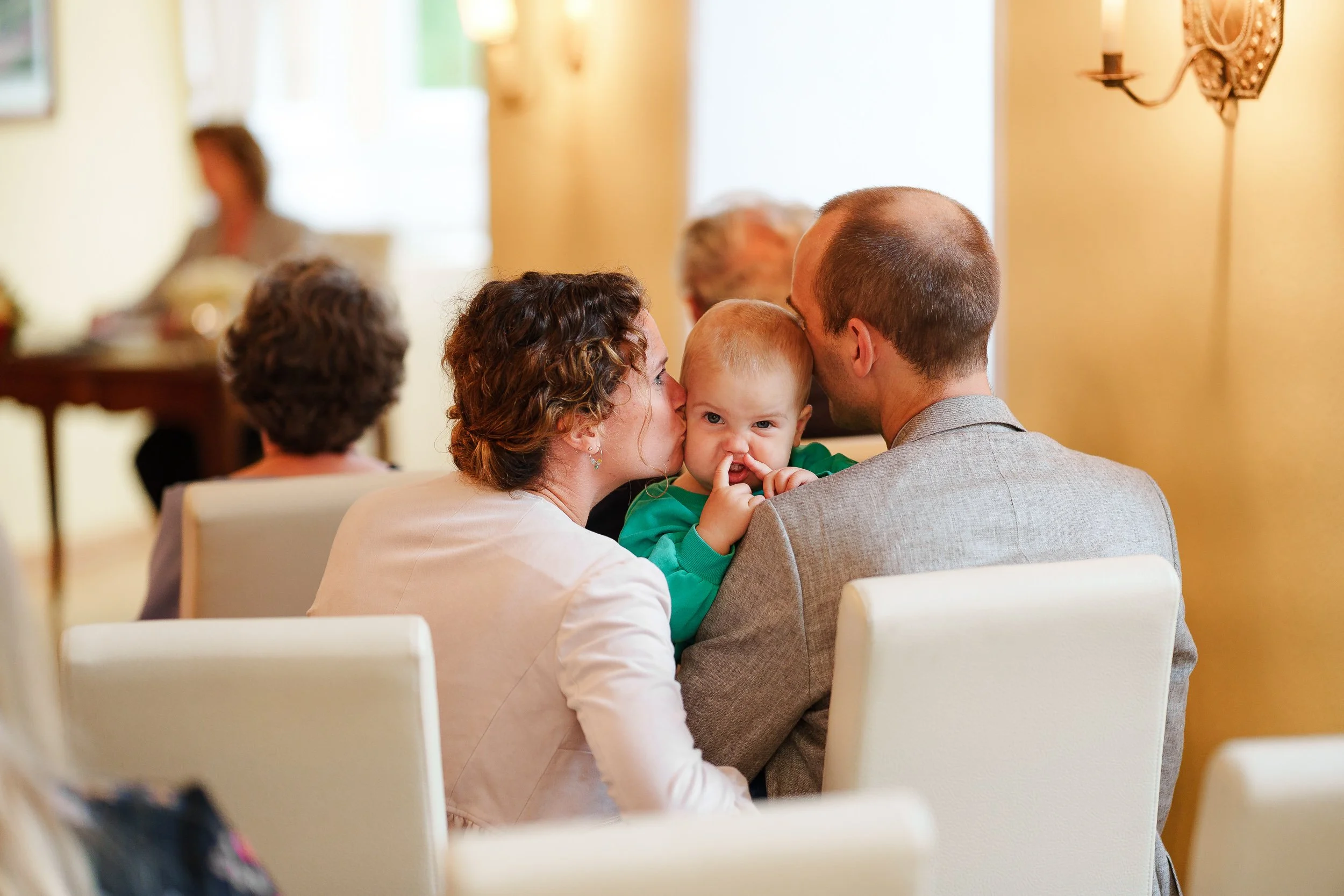 Familie bei einem Fest im Gespräch, dabei ein Kind mit Nase in Richtung Kamera.