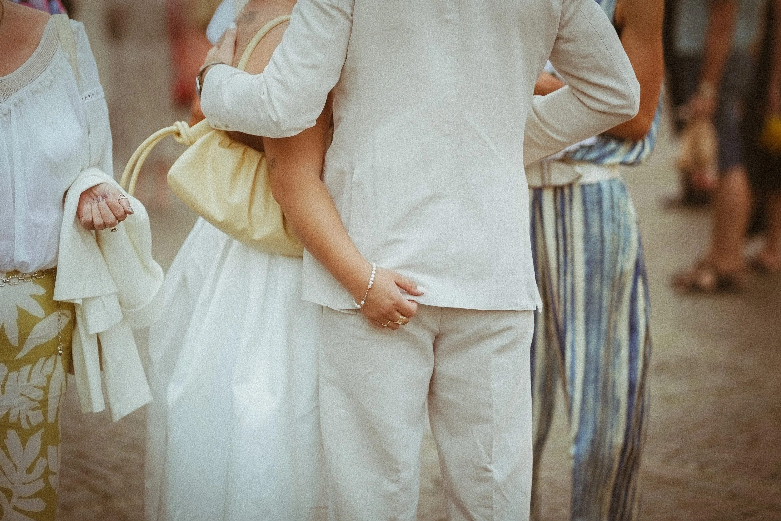Menschen in einem weißen, gestreiften und bunten Kleidung, die an einem warmen Tag draußen stehen.