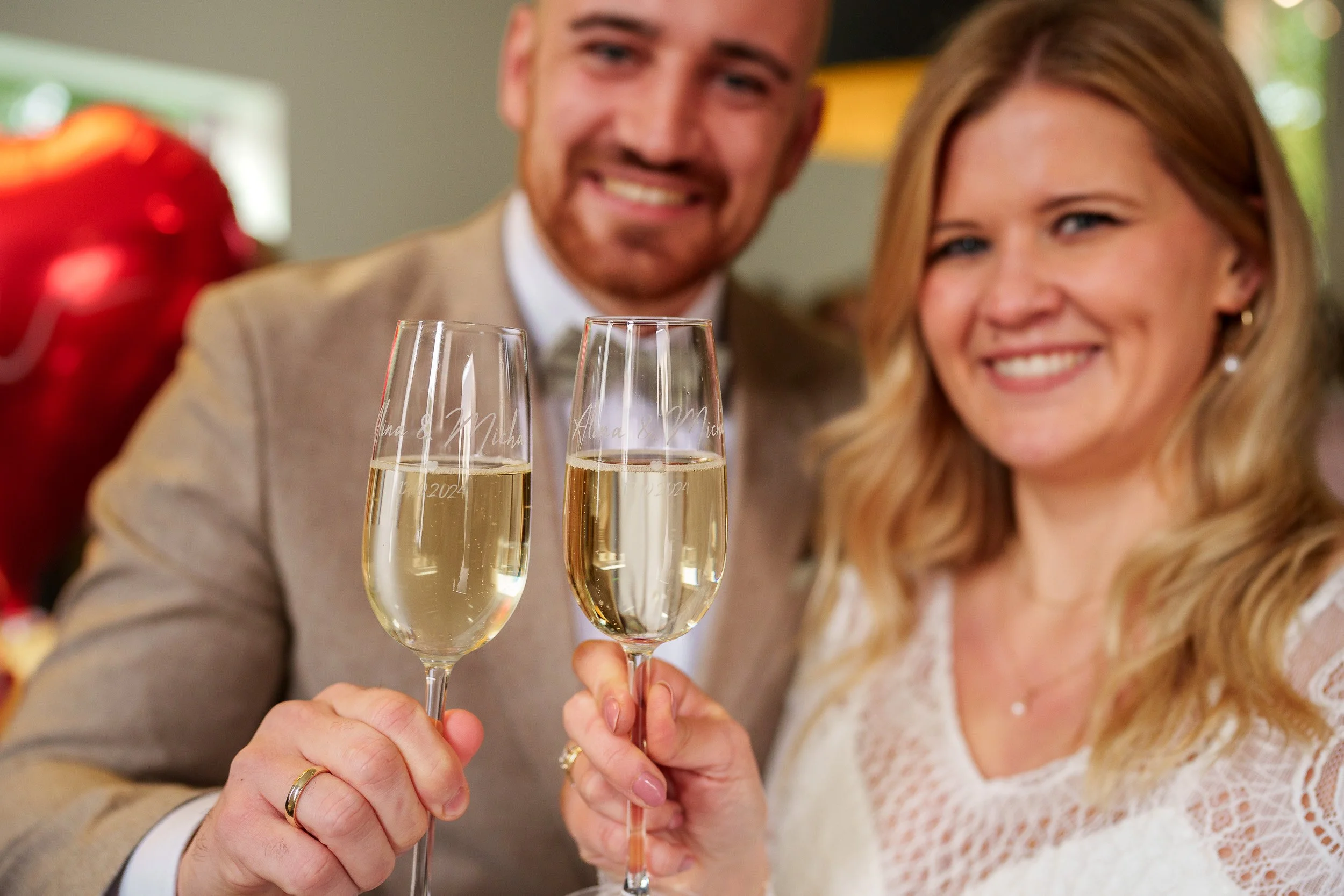 Ein lachendes Paar bei einer Feier, das auf ein Glas Sekt anstößt.