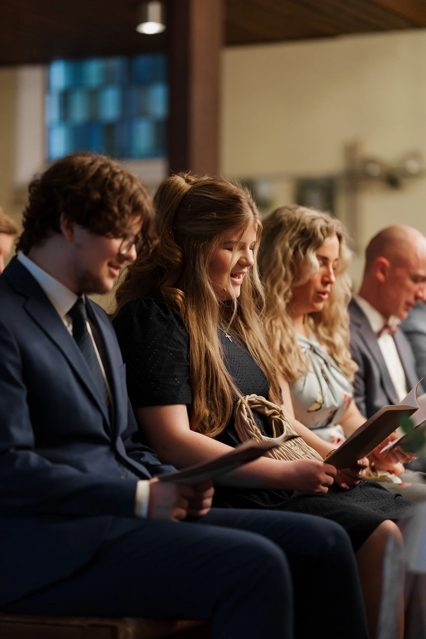 Menschen sitzen in einem Kirchenraum und lesen Gebetsbücher.