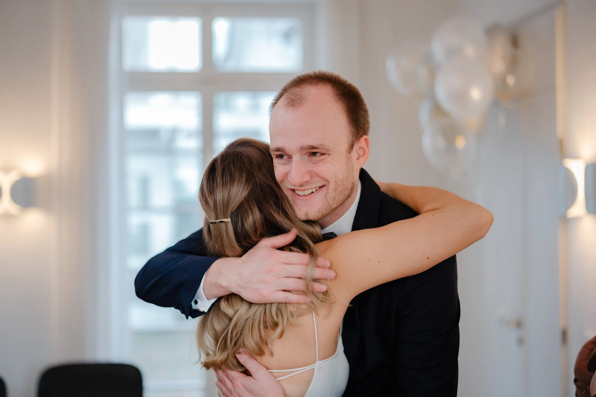 Ein Mann und eine Frau umarmen sich glücklich bei einer Feier, wahrscheinlich eine Hochzeit.