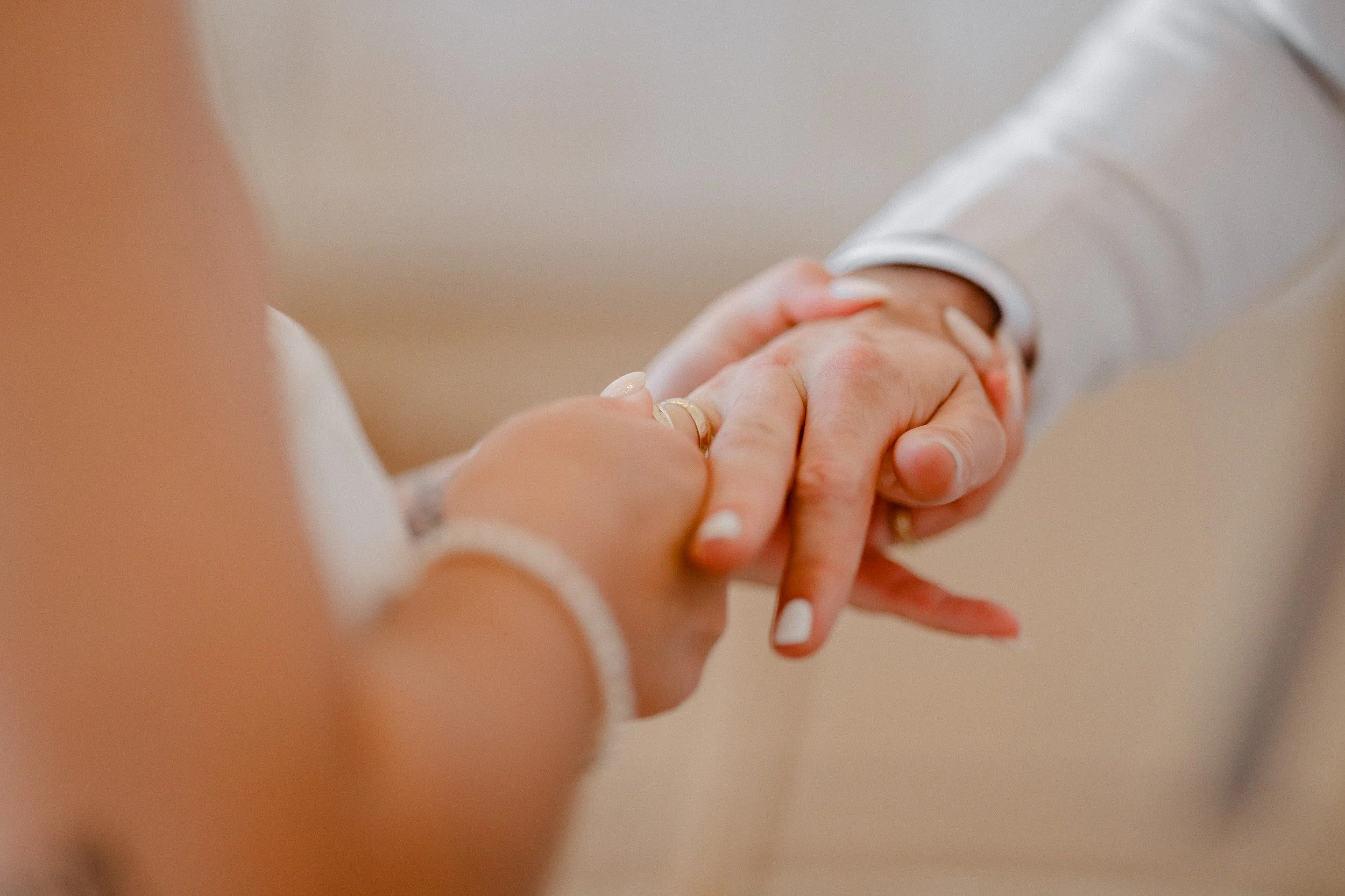 Nahaufnahme eines Händeschüttelns zwischen einem Mann in einem weißen Hemd und einer Frau mit französischen Nägeln und Schmuck.