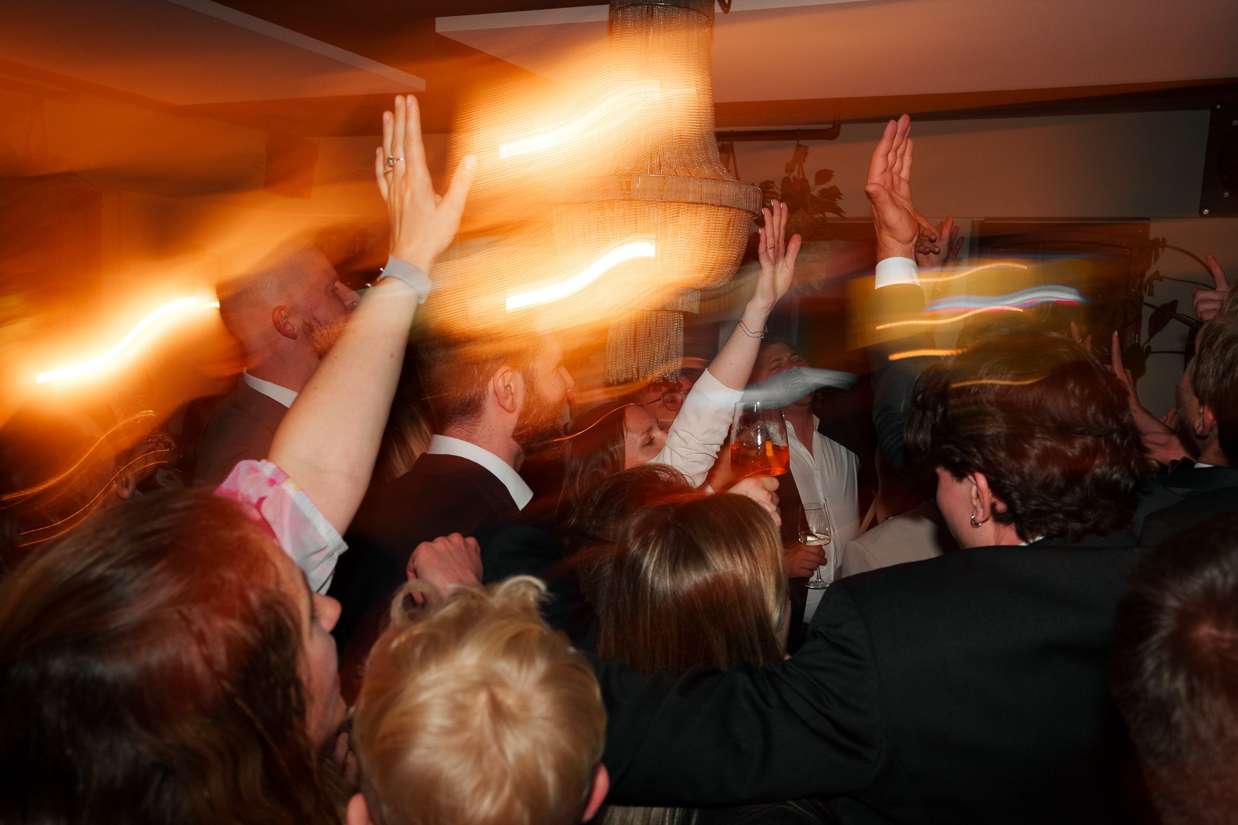 Menschen feiern auf einer Party mit buntem Licht und tanzen.
