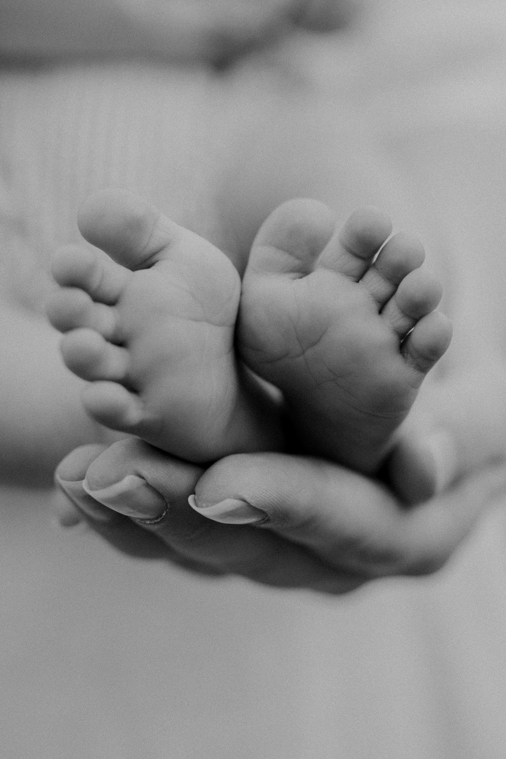 Nahaufnahme eines Erwachsenen, der ein Baby mit beiden Händen festhält.