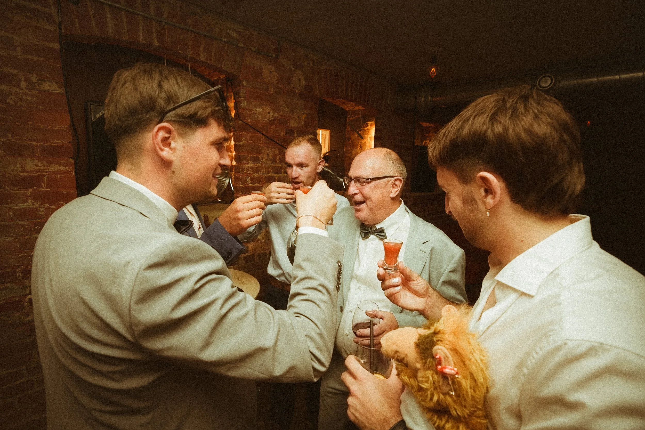 Eine Gruppe von Männern beim Trinken in einer Bar, einer hat einen kleinen Hund in den Armen.