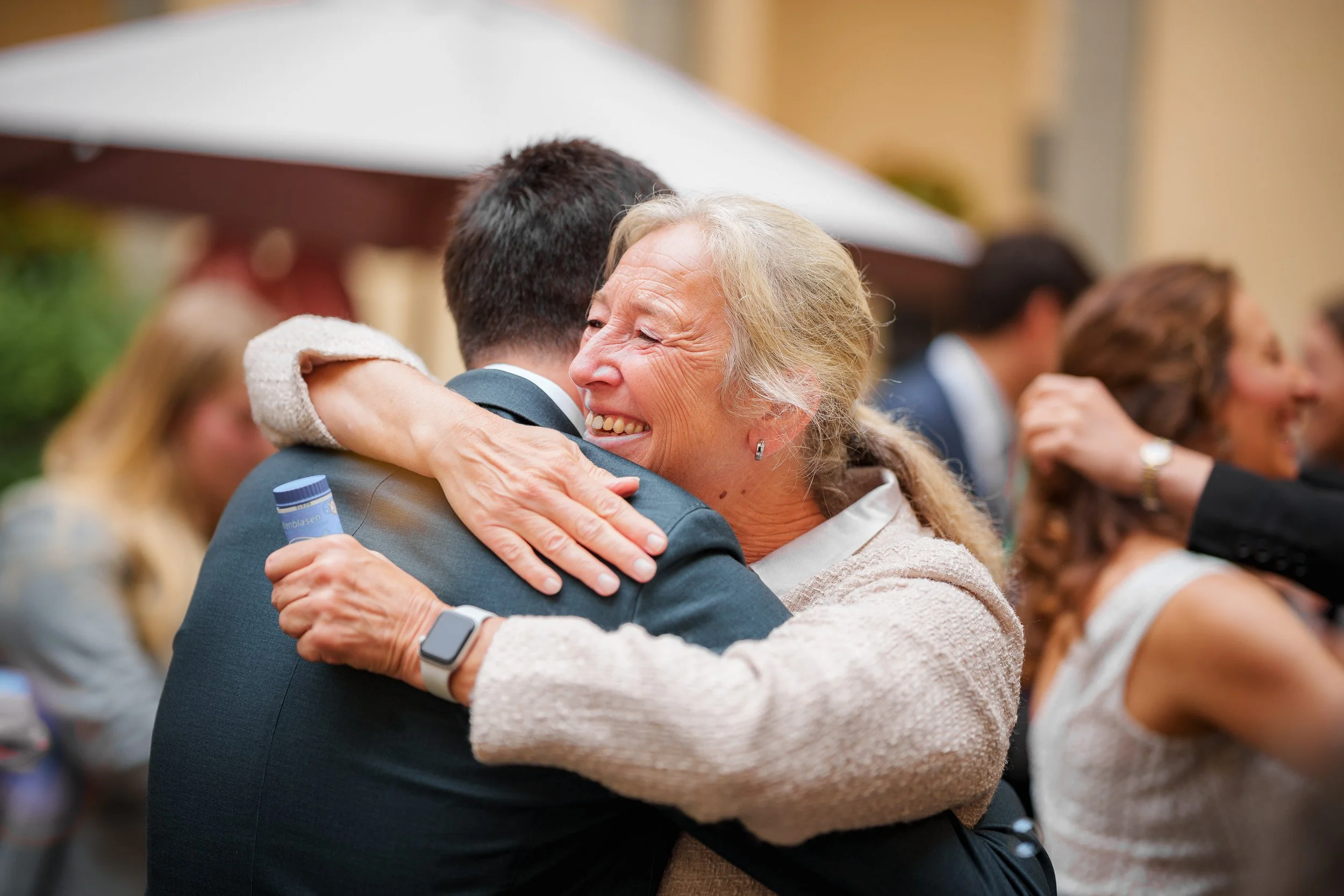 Ältere Frau umarmt lachend einen Mann bei einer Feier