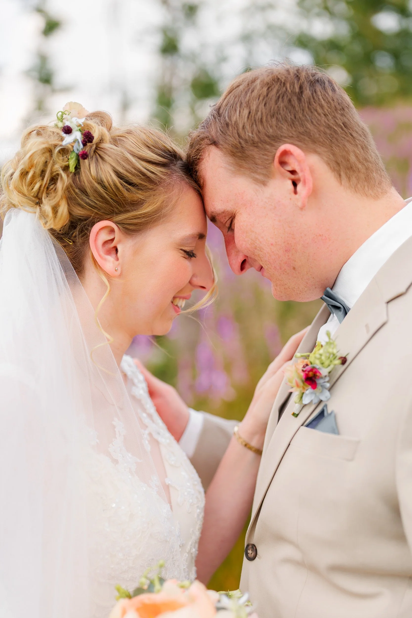 Braut und Bräutigam mit verschränkten Stirn und lächelnden Gesichtern bei ihrer Hochzeit im Freien