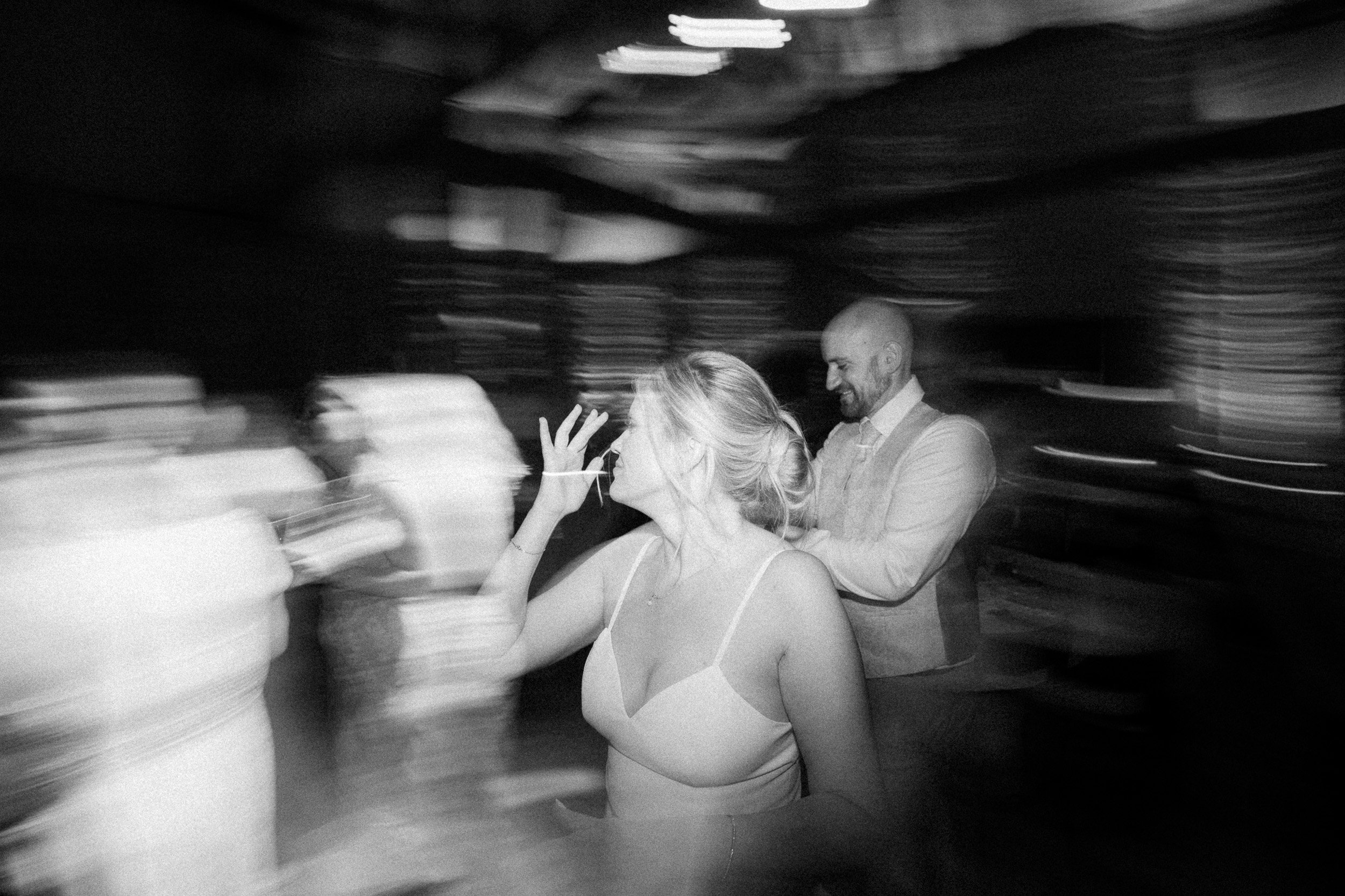 Ein Mann und eine Frau, die auf einer Tanzfläche im Schwarz-Weiß-Bild tanzen, mit verschwommenem Hintergrund.