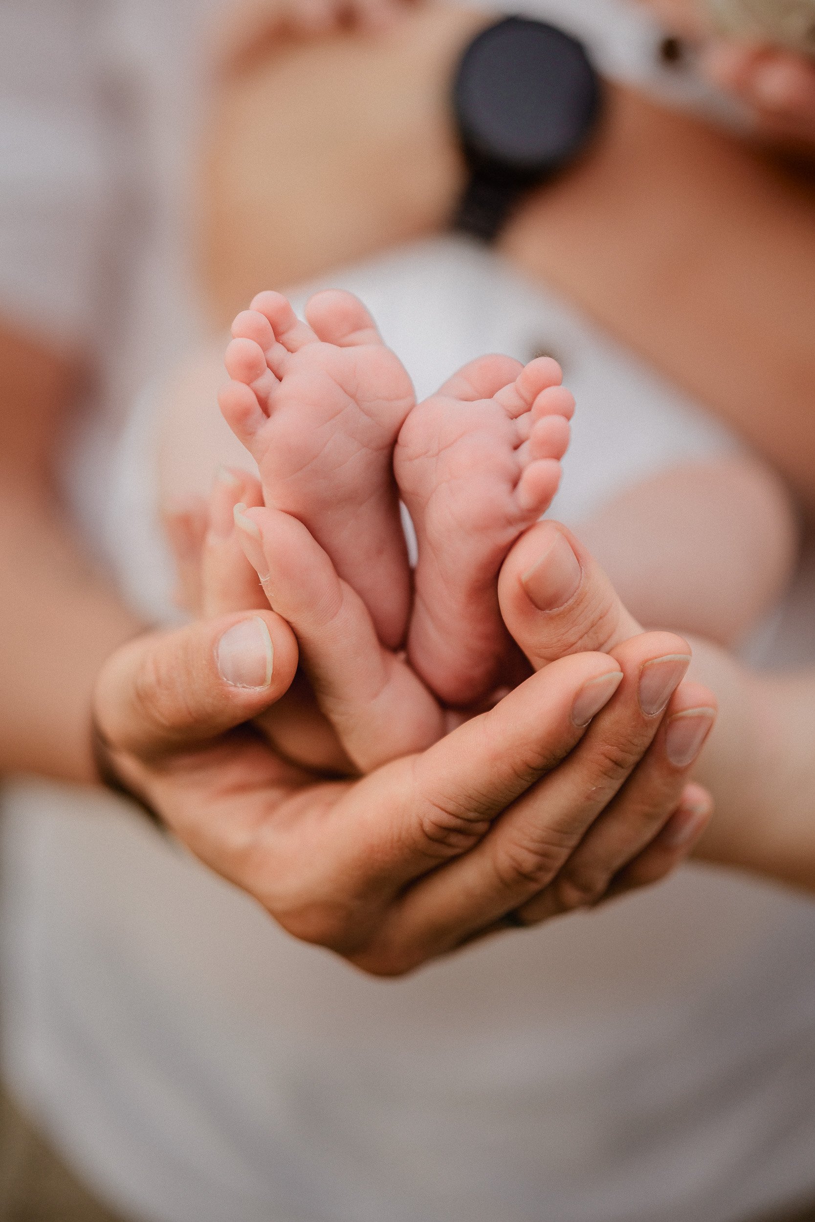 Nahaufnahme von einem Erwachsenen, der ein Neugeborenes liebevoll hält.