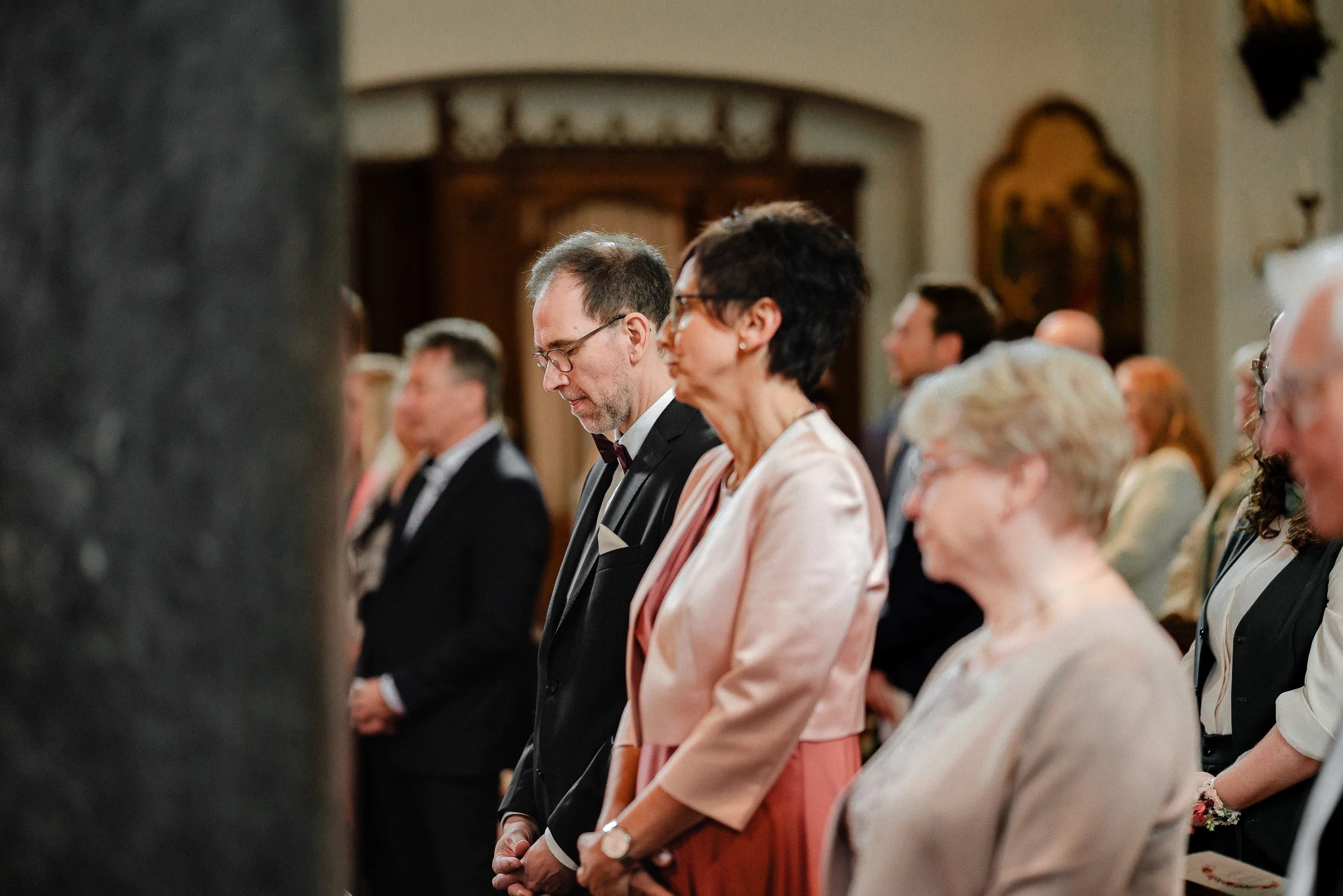 Menschen in formeller Kleidung beten in einer Kirche während einer Zeremonie.