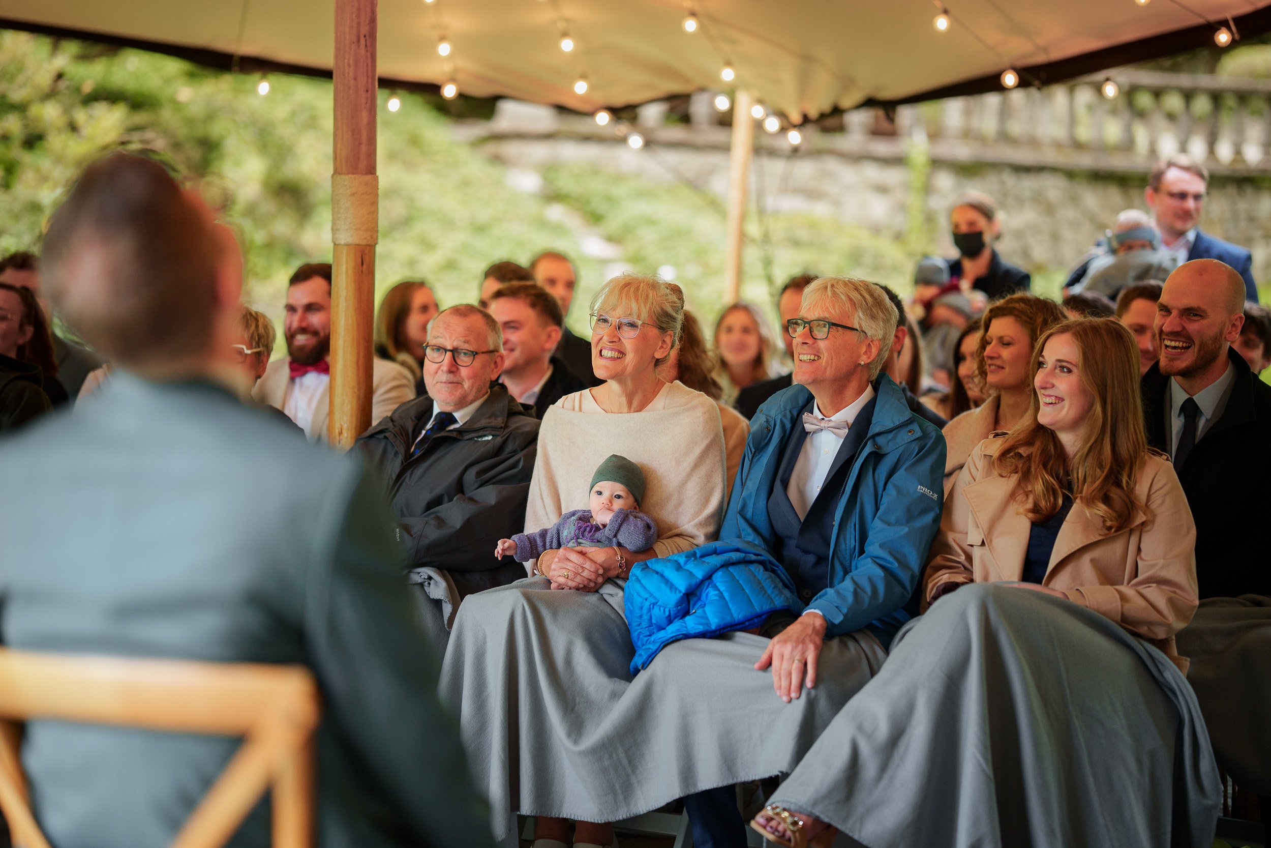 Menschen sitzen unter einem Zelt bei einer Veranstaltung, lacht und haben Spaß.