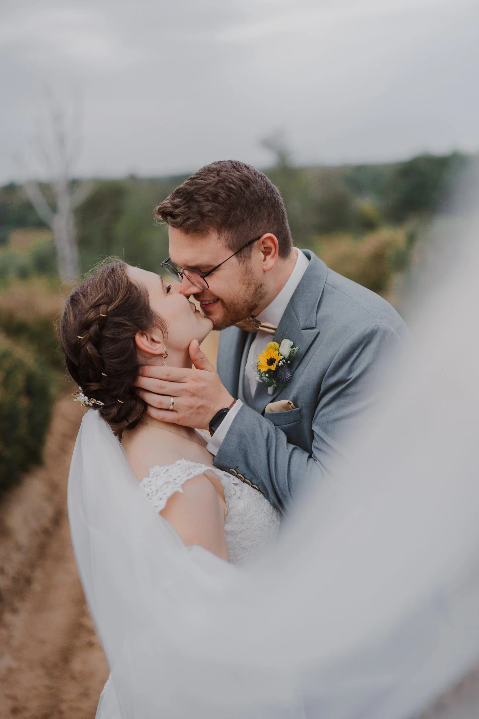 Ein Brautpaar küsst sich in einer Naturkulisse bei einer Hochzeit.