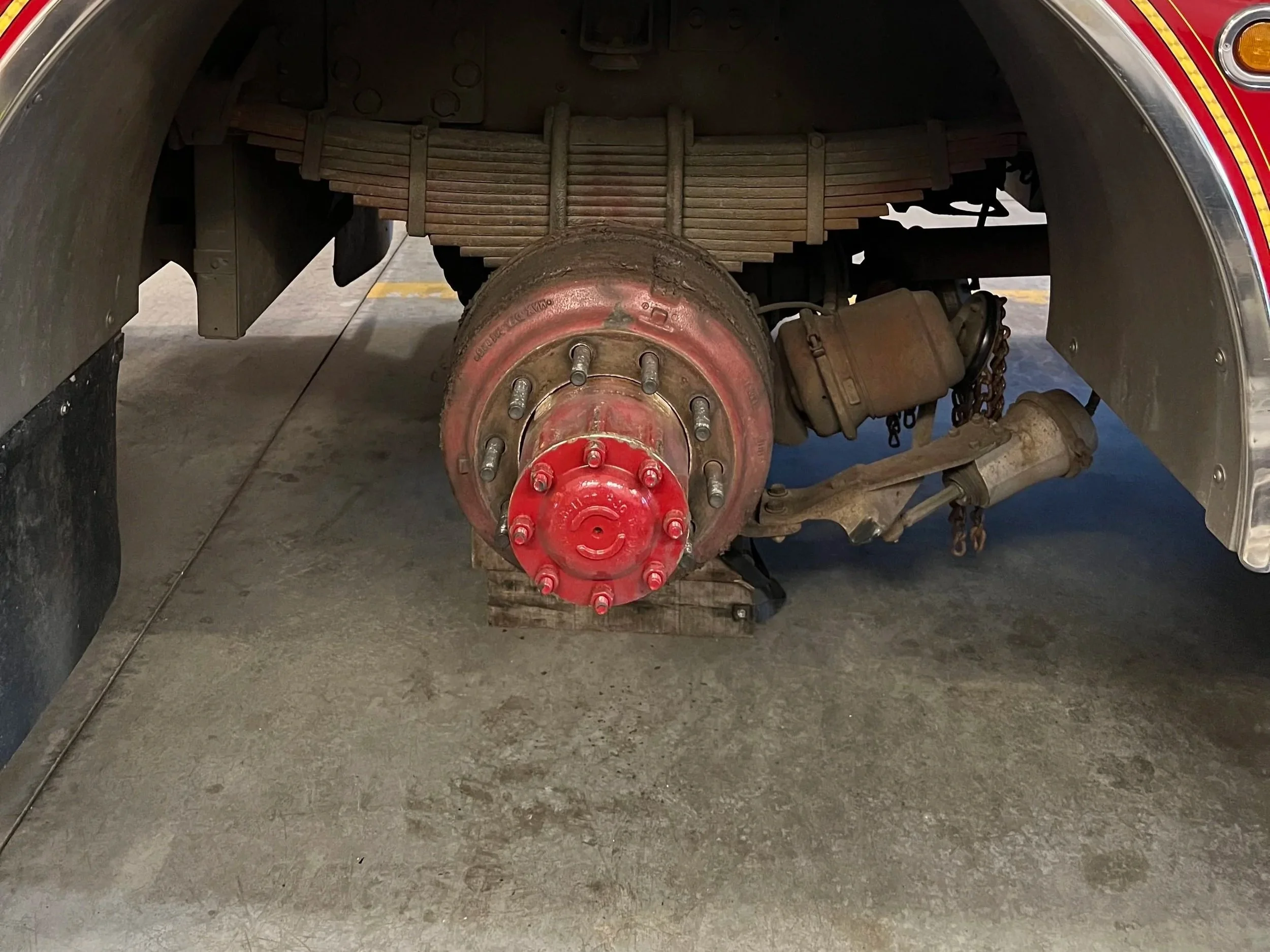 View under a vehicle showing the brake drum, suspension, and other components.