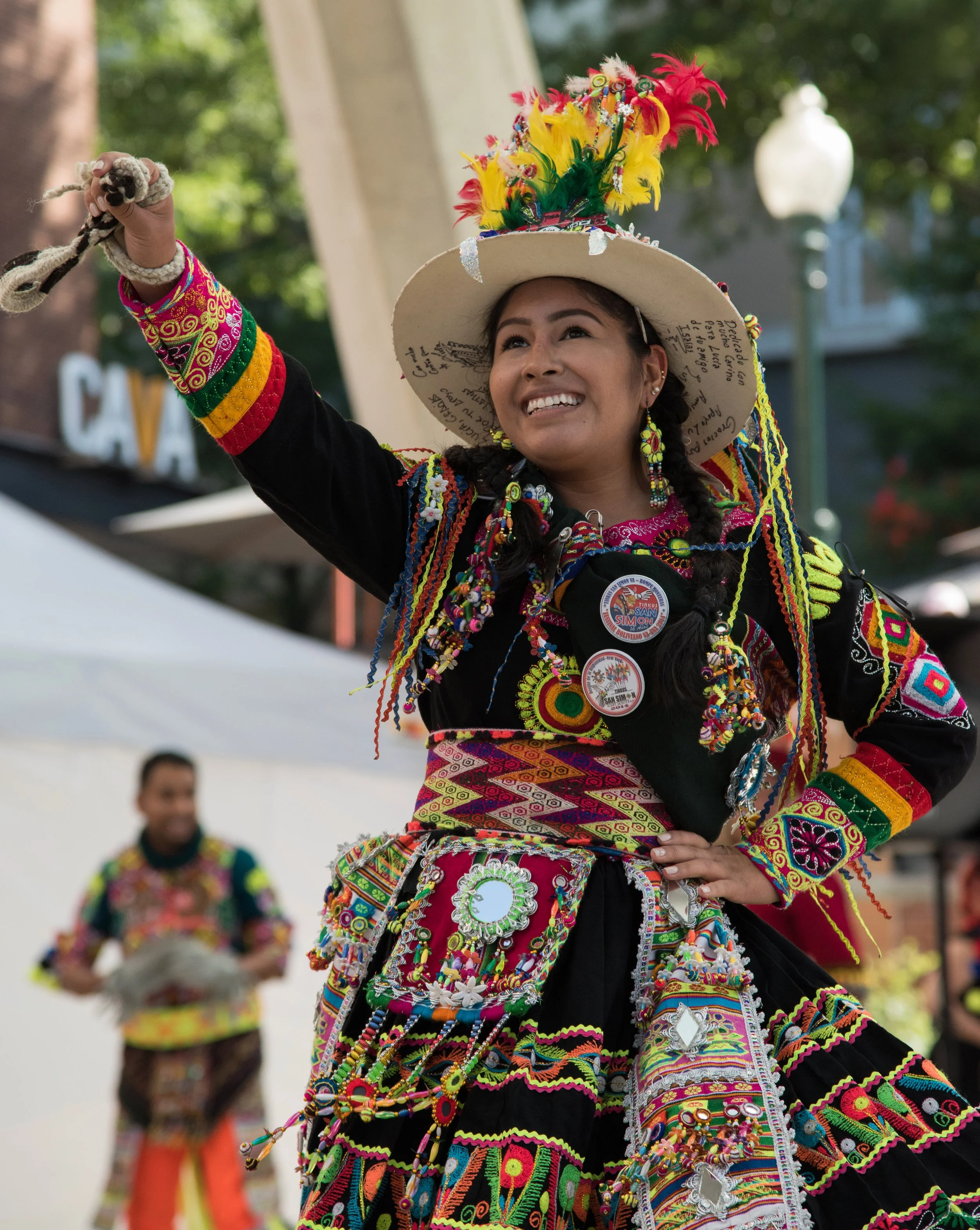 Woman in colorful traditional Mexican folk costume dancing and smiling during a cultural event.