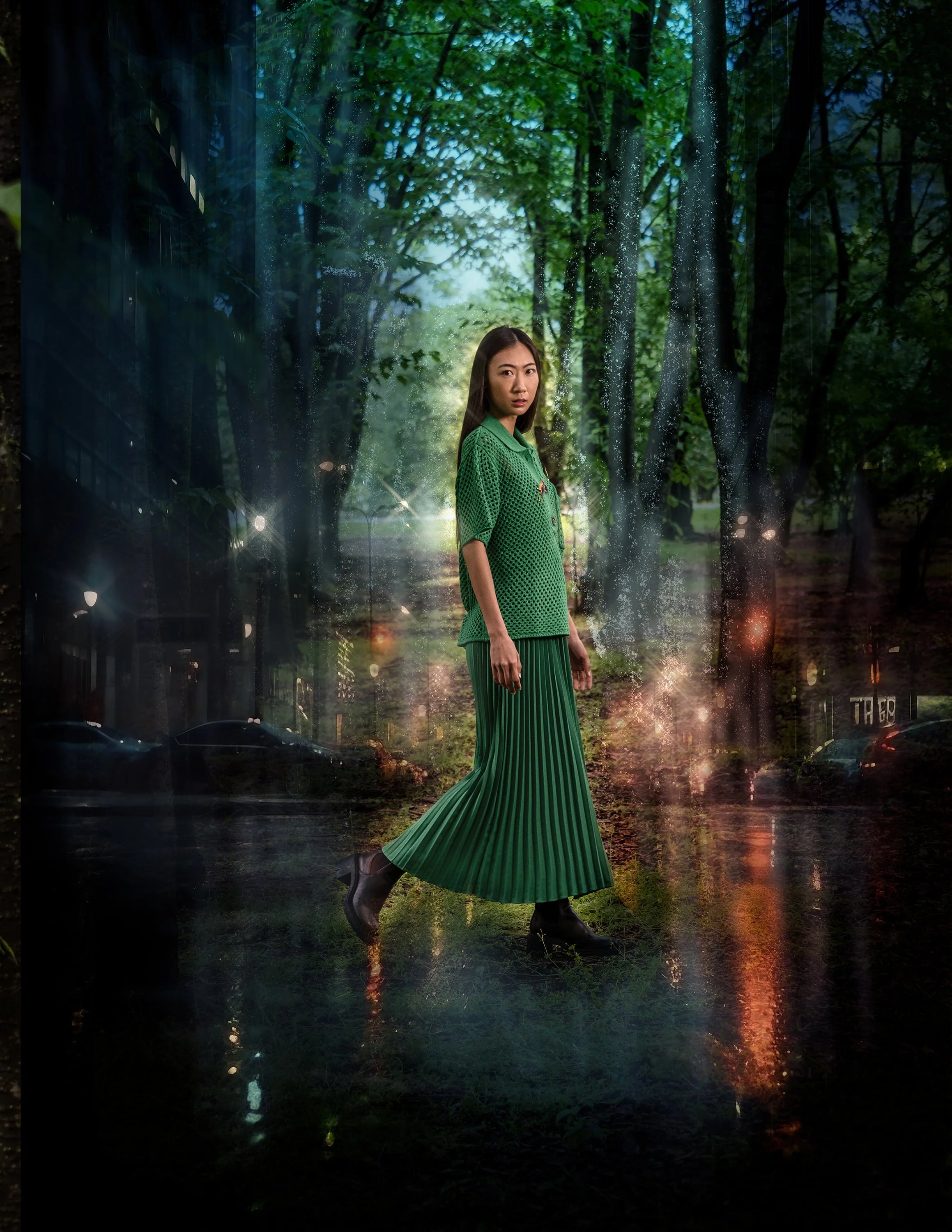 A woman in a green outfit standing in a forest at night, with reflections and light effects creating a surreal atmosphere.
