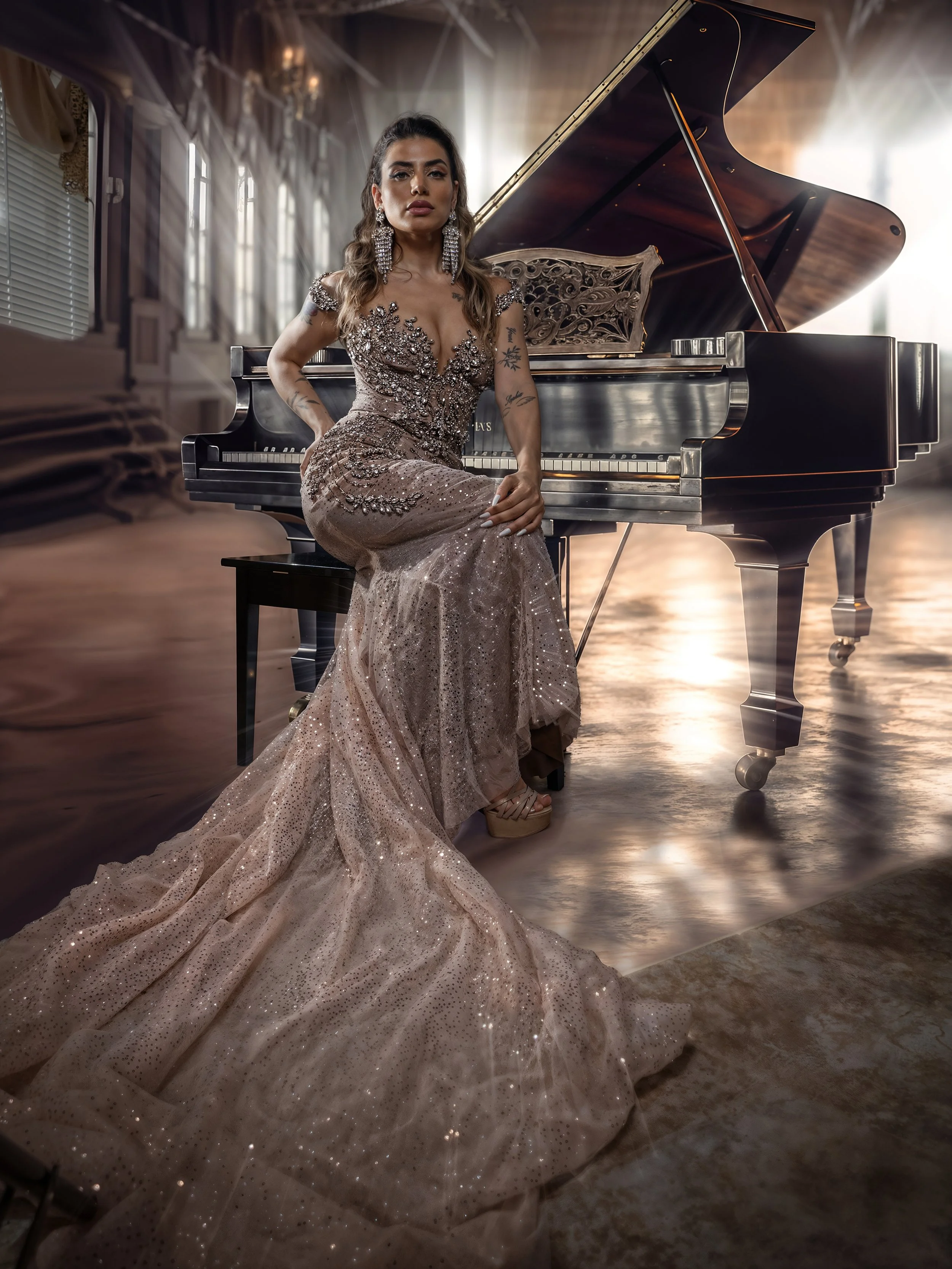 A woman in a sparkling, elegant gown seated beside a grand piano in a bright, spacious room with large windows.