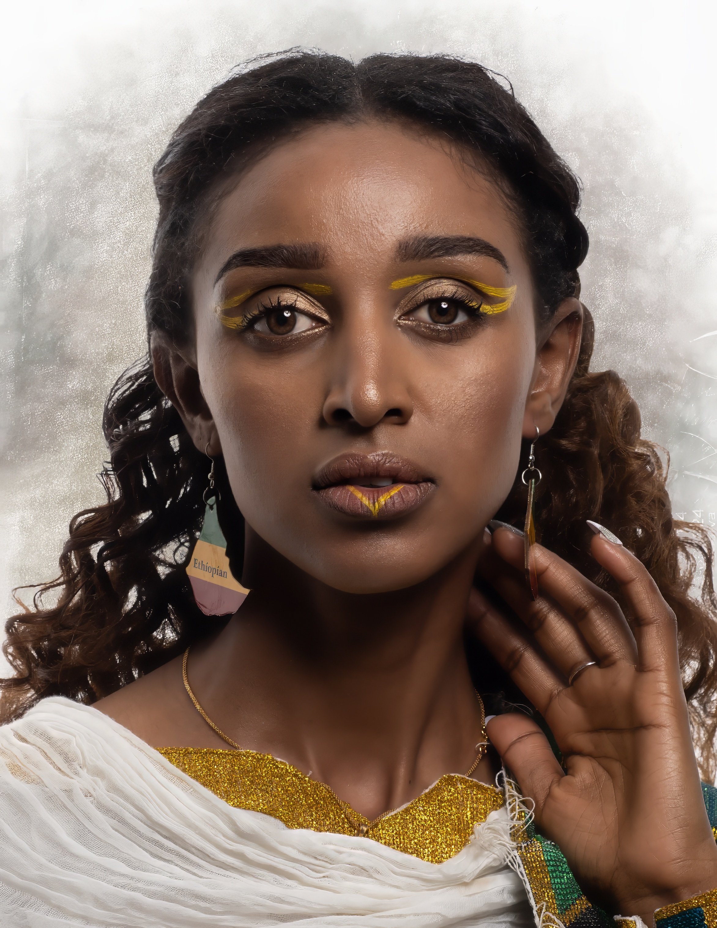 A woman with dark skin and curly hair wearing traditional Ethiopian earrings and clothing, with gold and yellow makeup accents around her eyes and lips, and a neutral background.