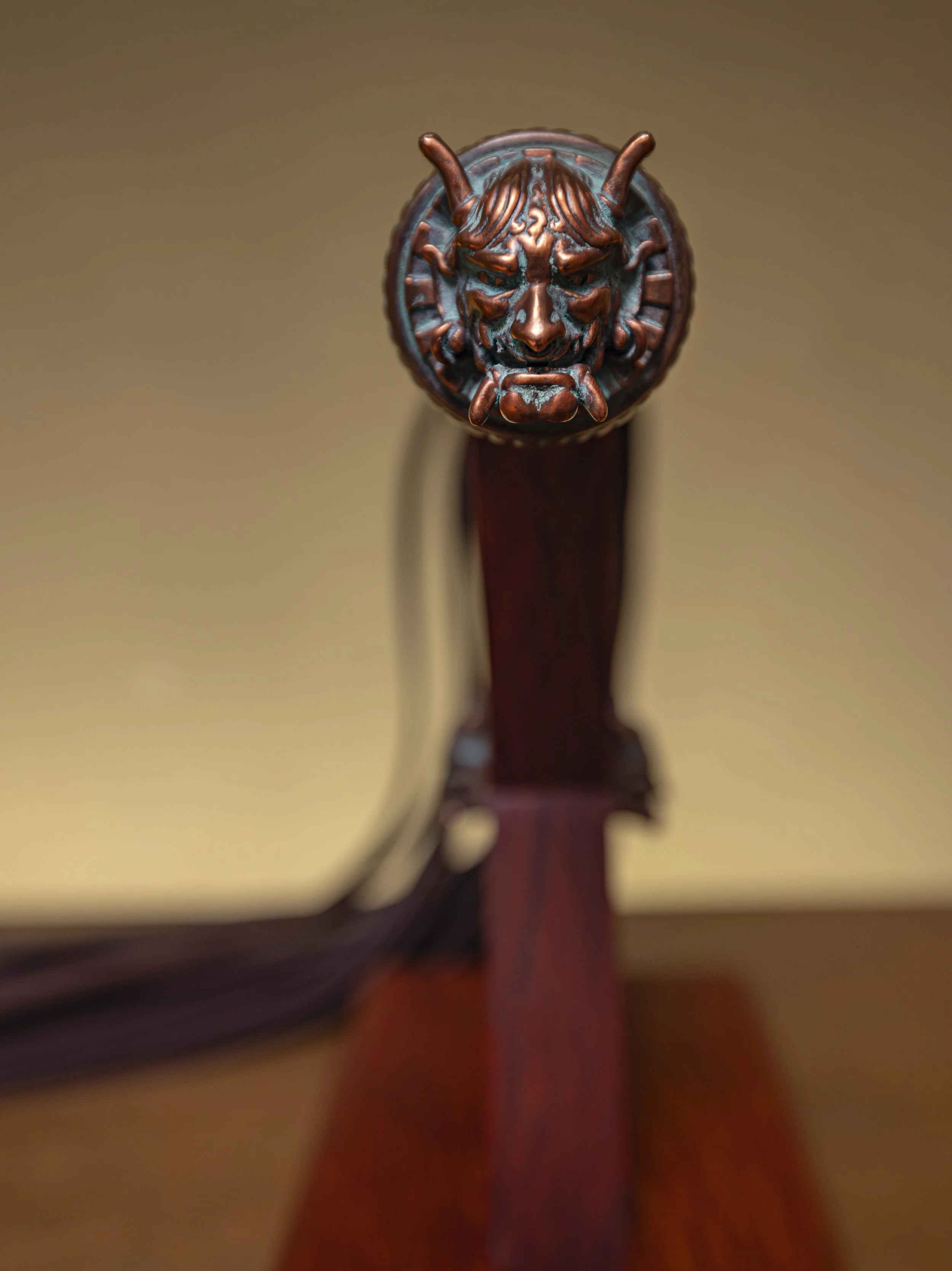 Close-up of a wooden rifle stock with an ornate carved lion's head on the butt. The background is blurred.