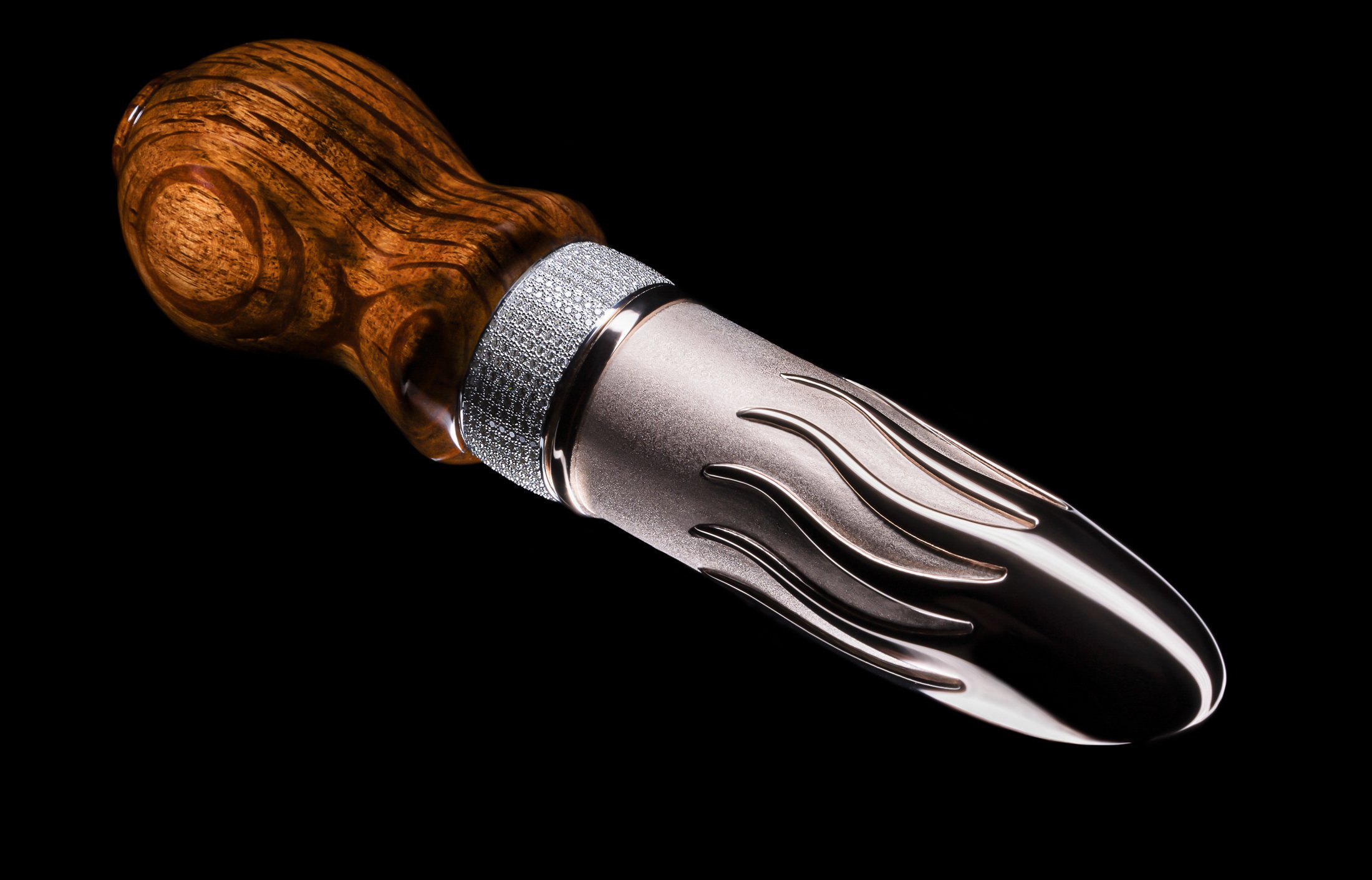 A knife with a wooden handle and a metallic blade featuring flame-like engravings.