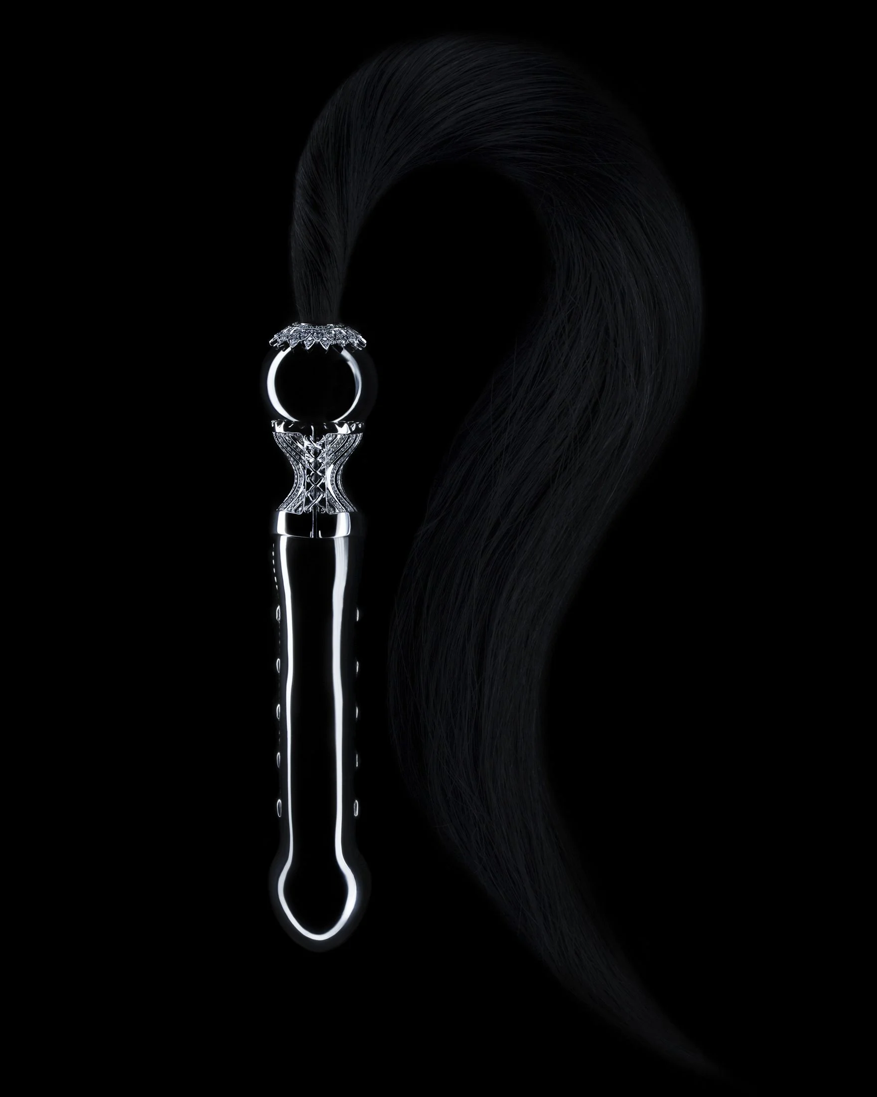 A hairbrush with a black handle and metal bristles, attached to a long, thick, black hair that curves to the right against a black background.