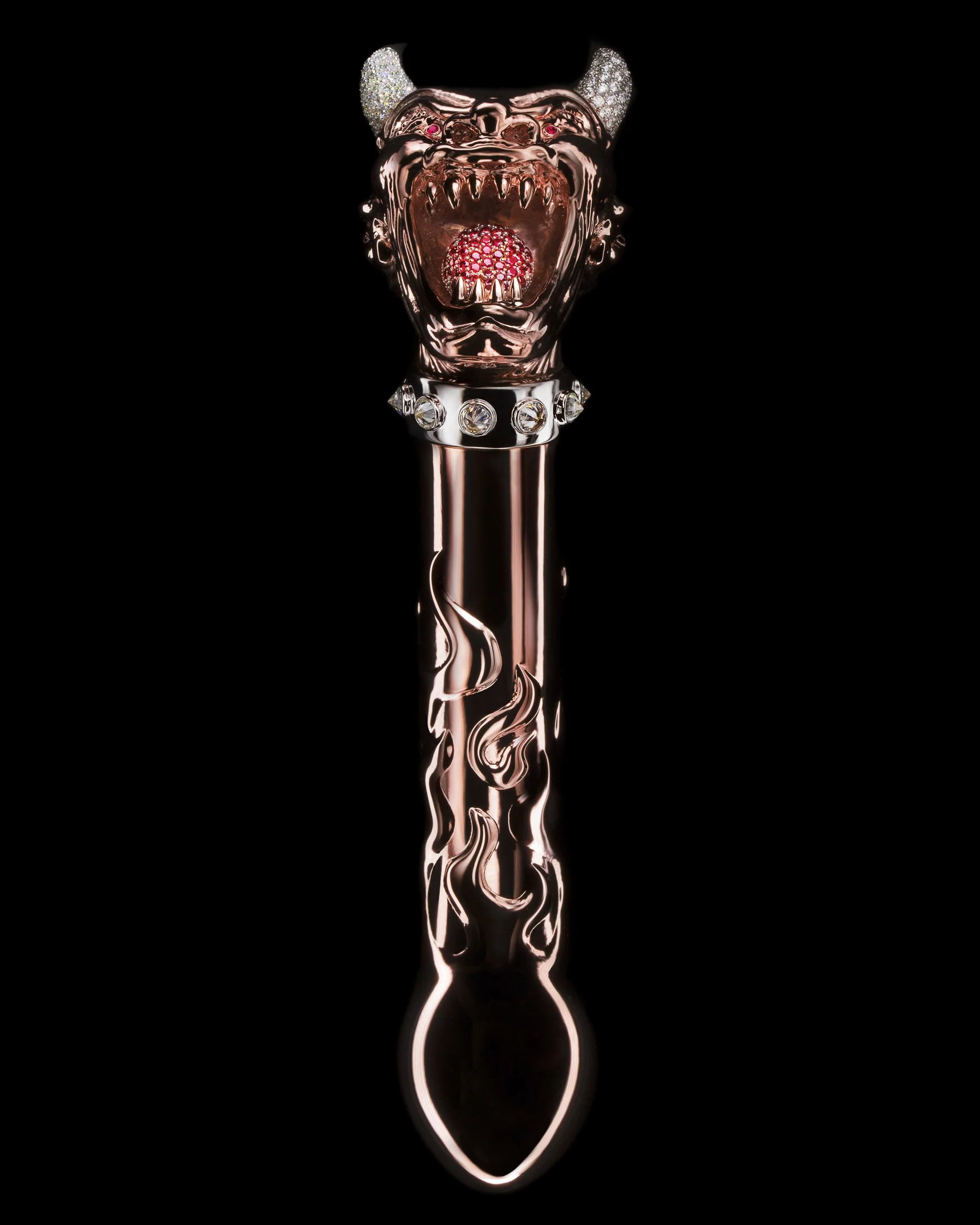 A metallic scepter with a lion or dog head at the top, decorated with diamonds and a red gemstone in its mouth, set against a black background.