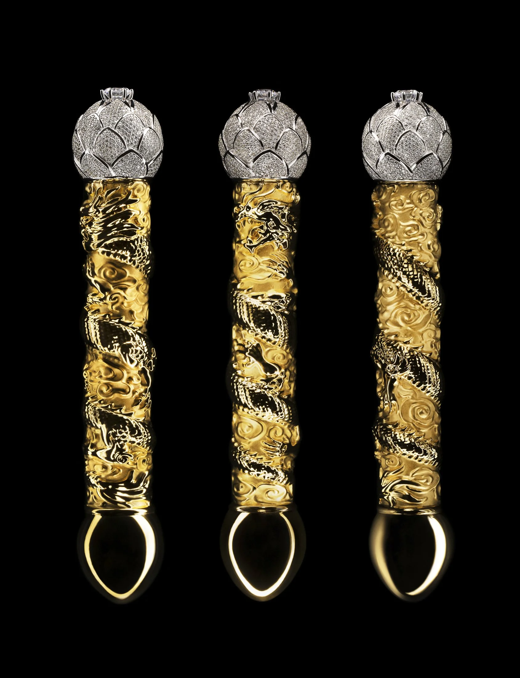 Three decorative objects with black backgrounds. Each has a silver, diamond-encrusted top resembling an artichoke or floral design, attached to a spiral gold handle with intricate dragon motifs.