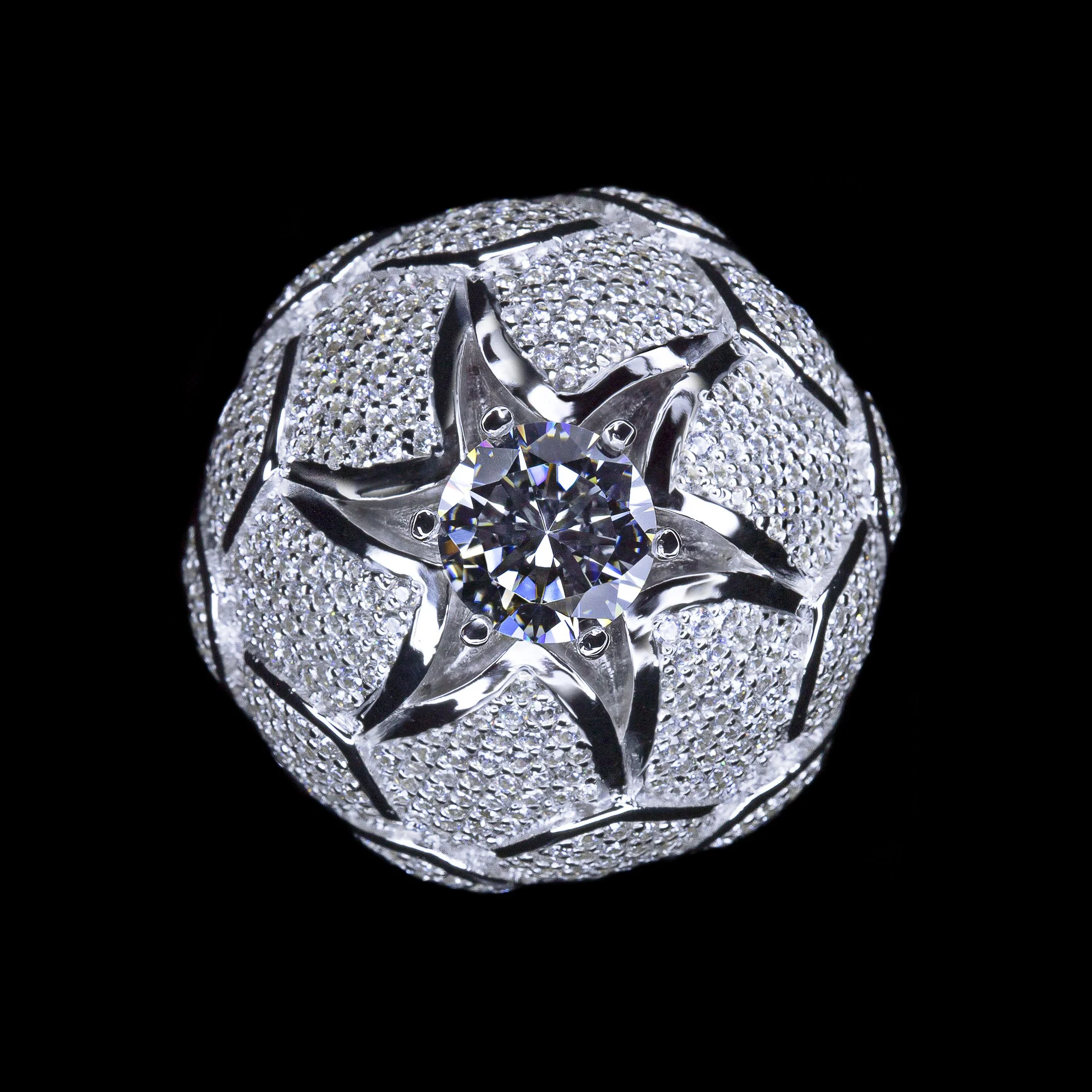 A spherical diamond-encrusted jewelry piece with a large central diamond set in a star-shaped silver setting, against a black background.
