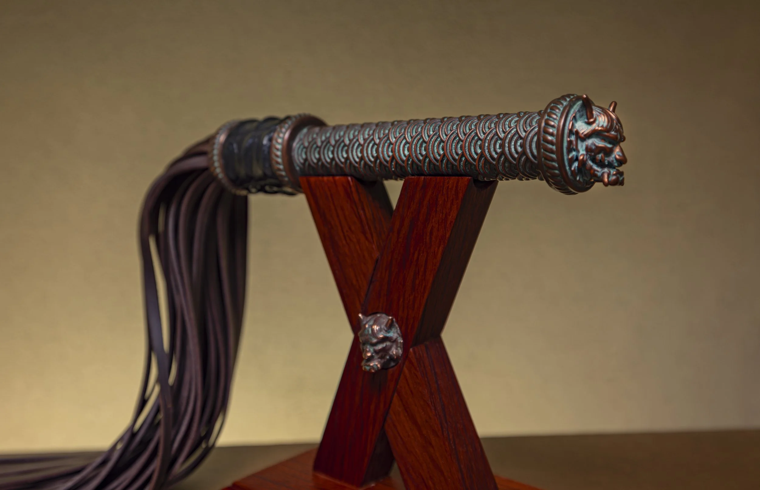 Decorative sword with a detailed dragon or demon head on the guard, displayed on a wooden stand.