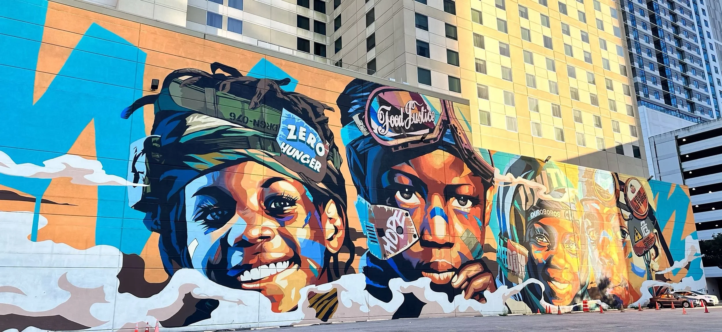 Colorful mural featuring three women with different hairstyles and headwear, with vibrant abstract background.